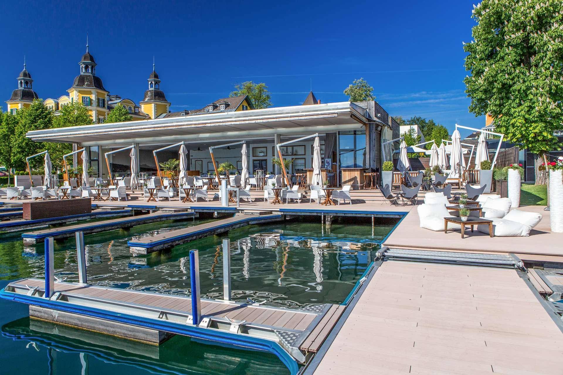 Restaurant am Wasser mit Bootsanlegestellen und Außenbereich unter blauem Himmel.
