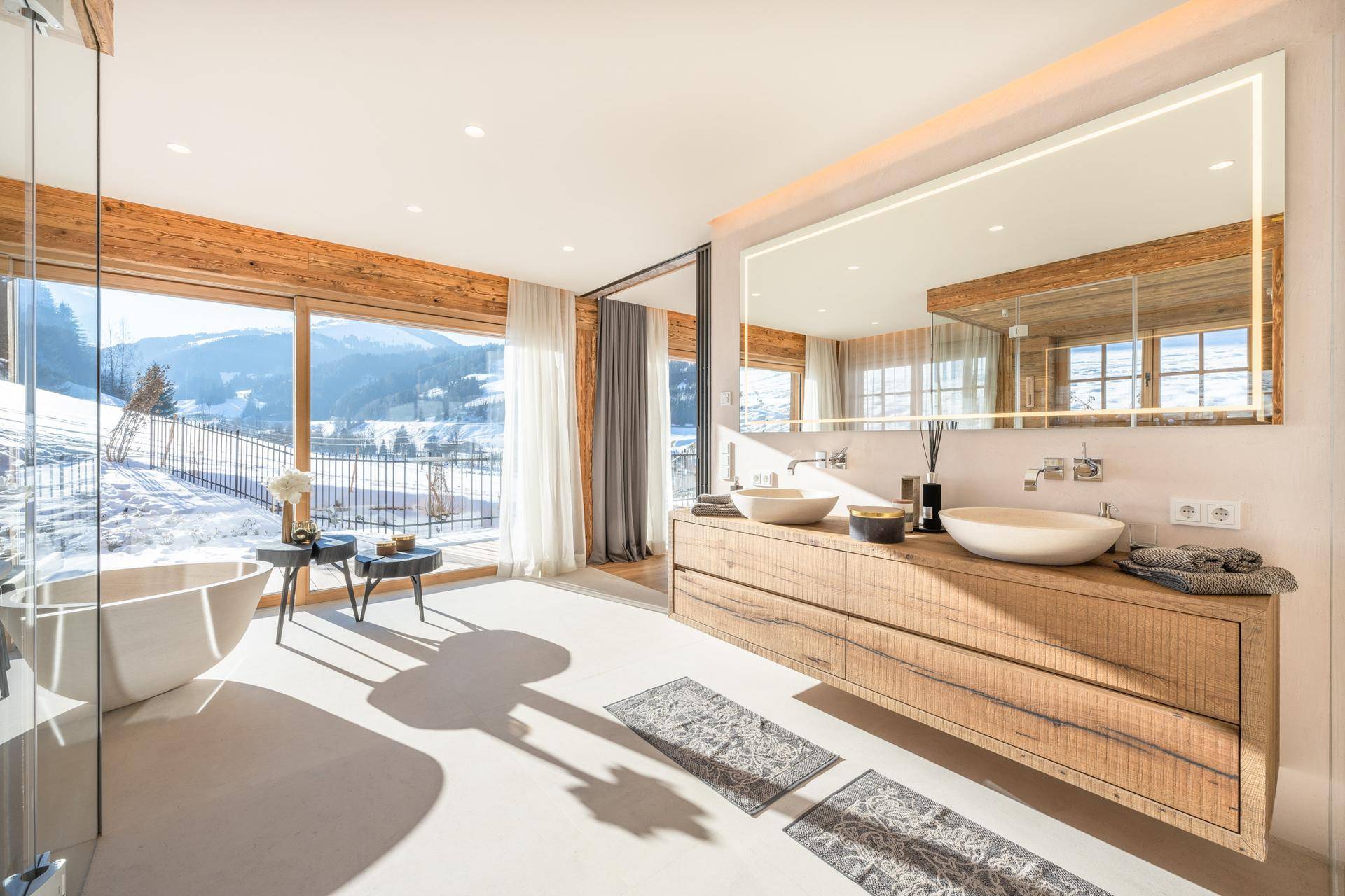 Geräumiges Badezimmer mit Doppelwaschbecken, großer Badewanne und Panoramablick auf die Winterlandschaft.