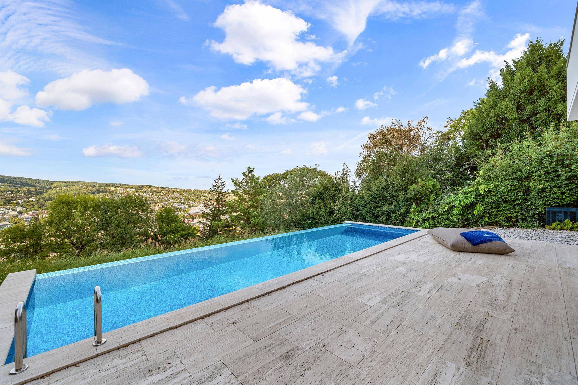 Eleganter Infinity-Pool mit gefliestem Rand und weitem Blick über die grüne Hügellandschaft.