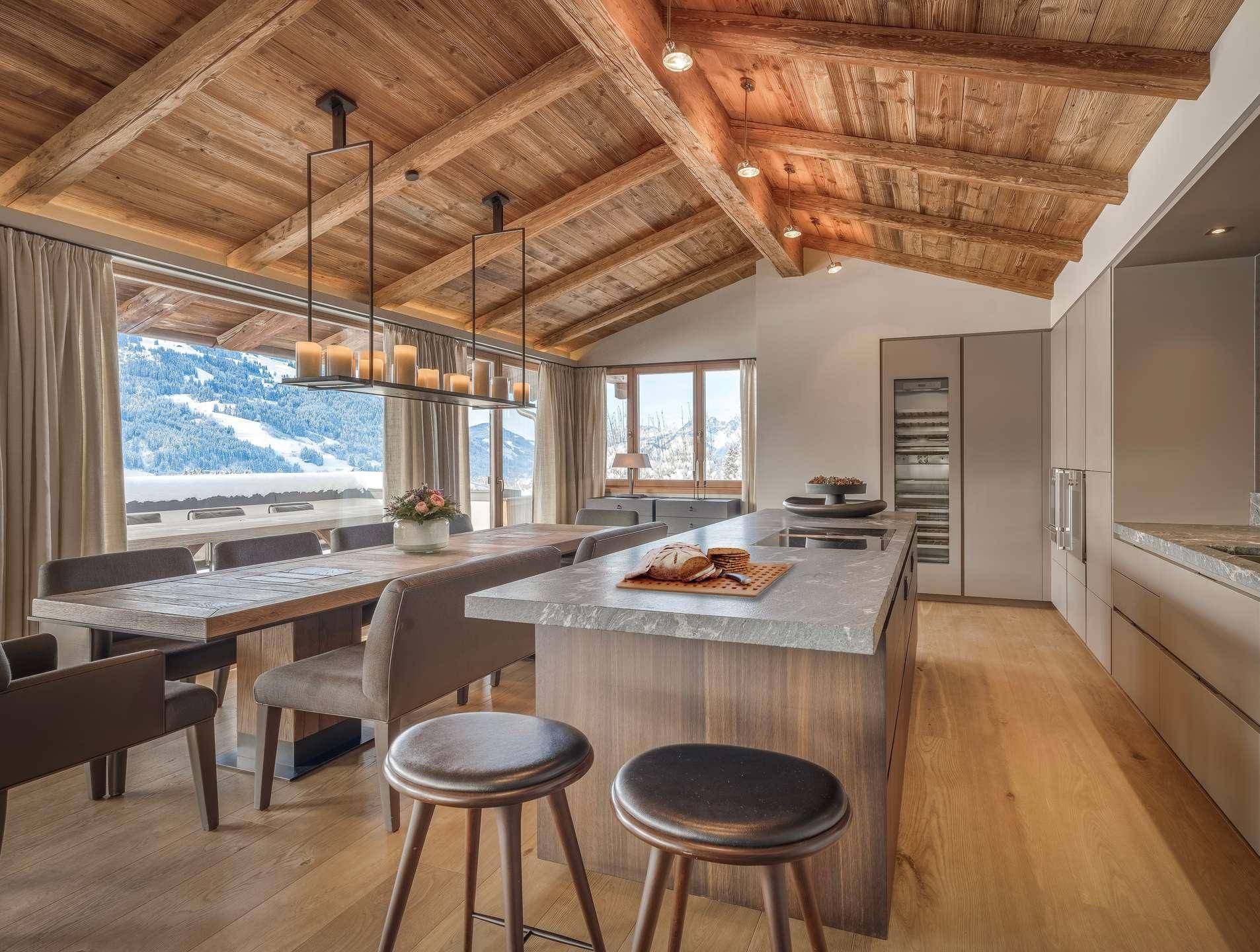 Moderne offene Küche mit Kochinsel, Essbereich und beeindruckendem Blick auf die verschneiten Berge.