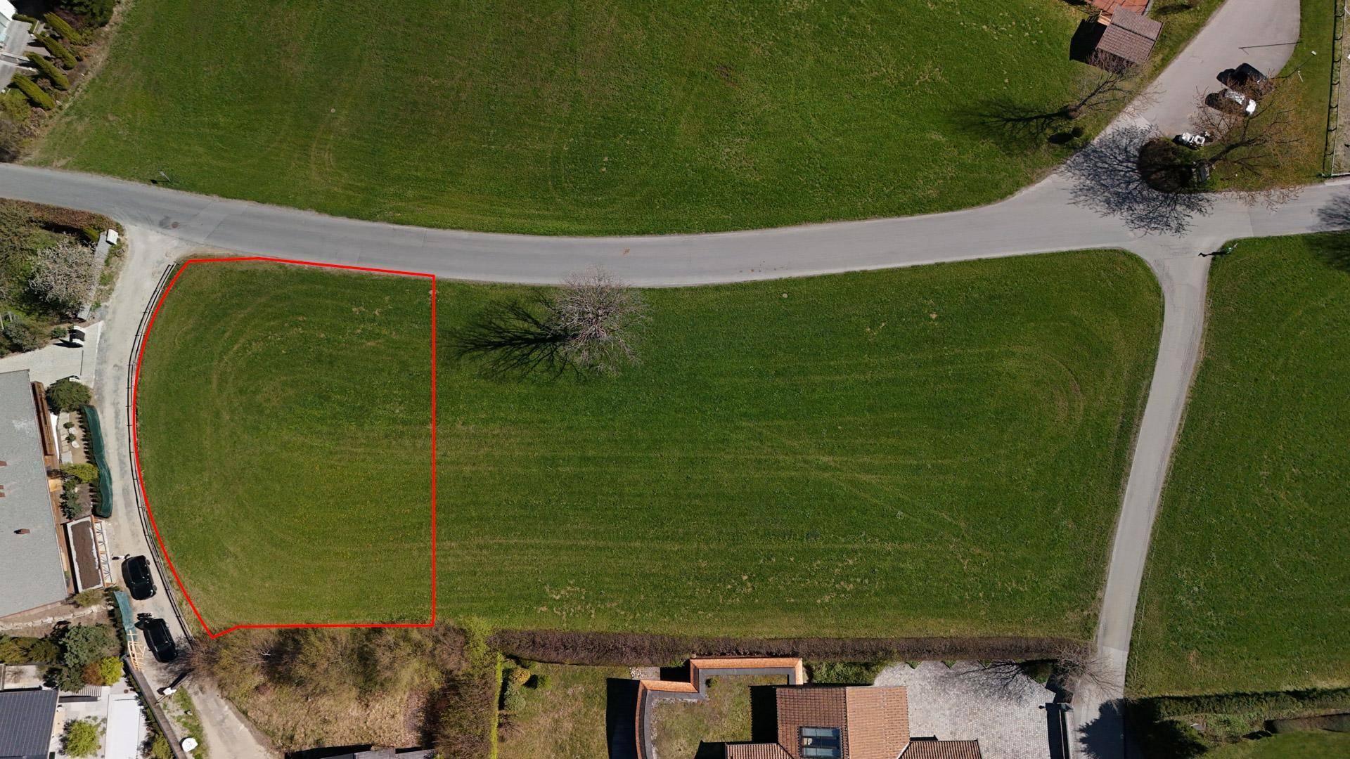 Luftaufnahme eines rot umrandeten Grundstücks mit Zufahrtsstraßen und angrenzenden Gebäuden.