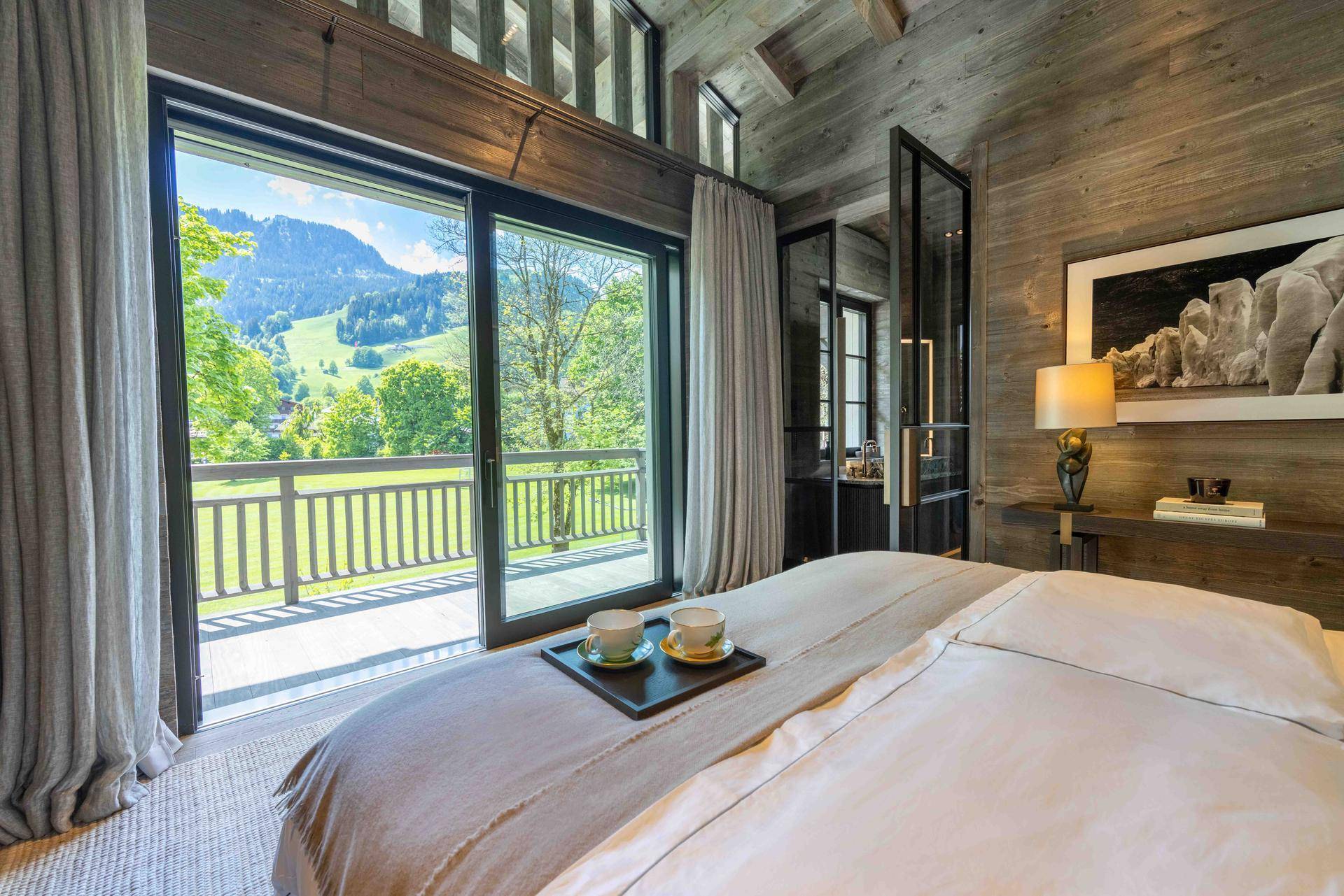 Schlafzimmer mit großem Bett, Holzbalkendecke und Panoramablick auf die Berge.