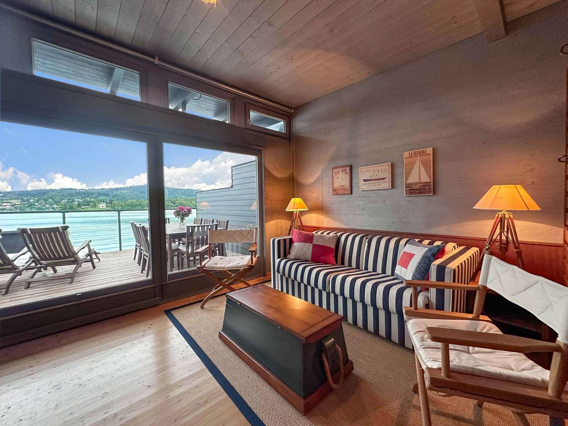 Gemütliches Wohnzimmer im maritimen Stil mit gestreiftem Sofa und Seeblick von der Terrasse.