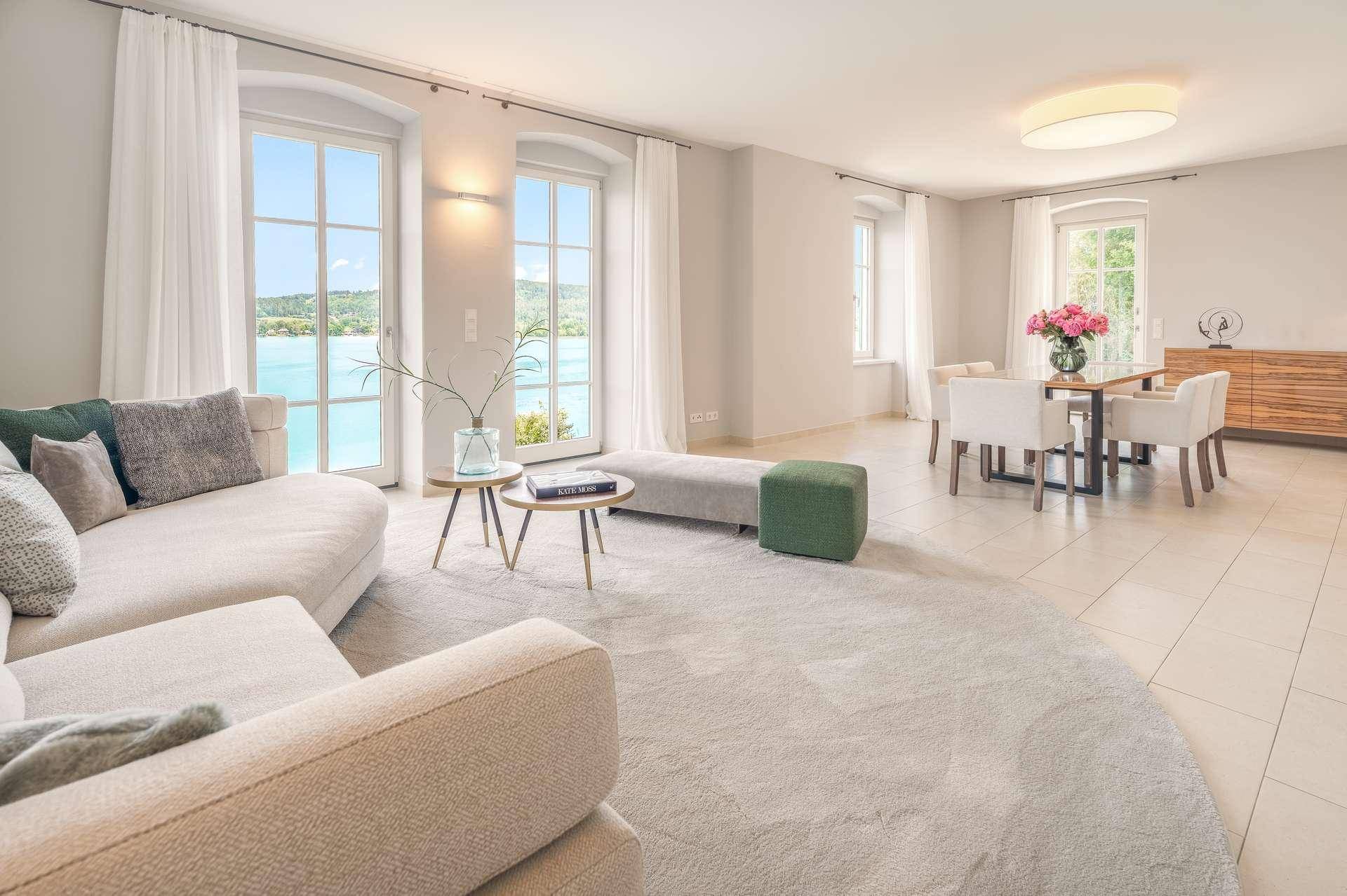 Lichtdurchfluteter Wohn-Essbereich mit Seeblick, großen Fenstern und modernem Interieur.