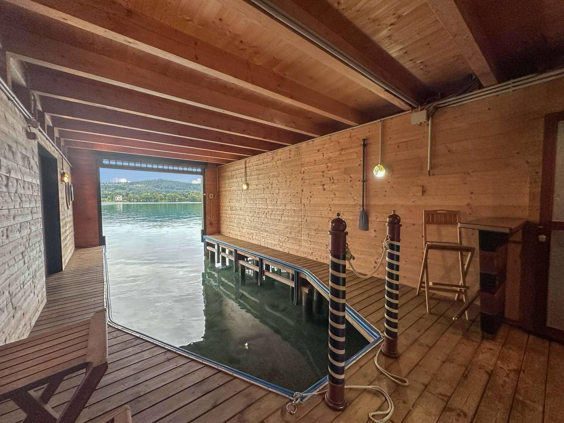 Rustikaler Innenraum eines Bootshauses mit Holzwänden und direktem Zugang zum Wasser.