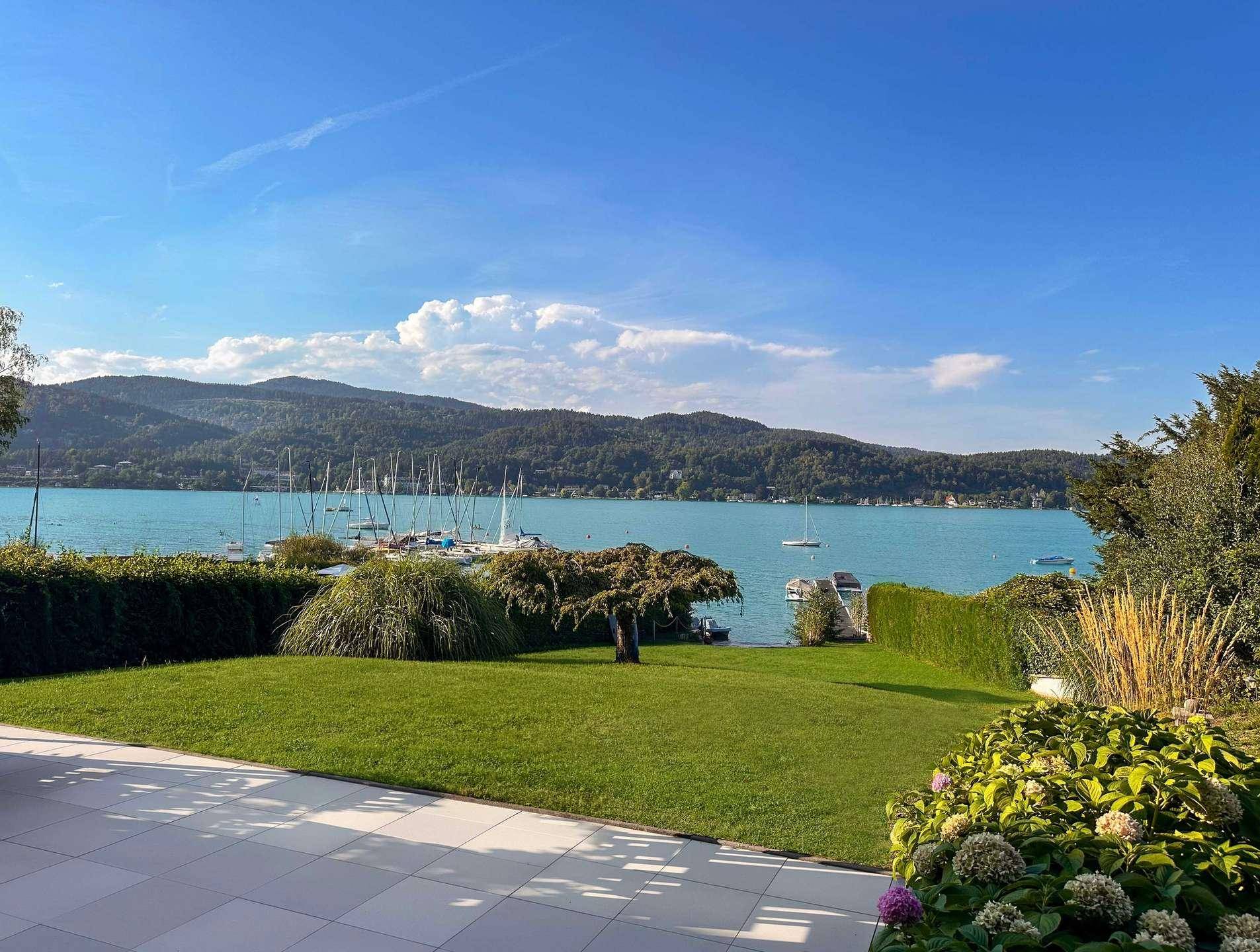 Wunderschöner Garten mit gepflegtem Rasen und großer Terrasse, bietet einen atemberaubenden Blick auf den See und die Berge.