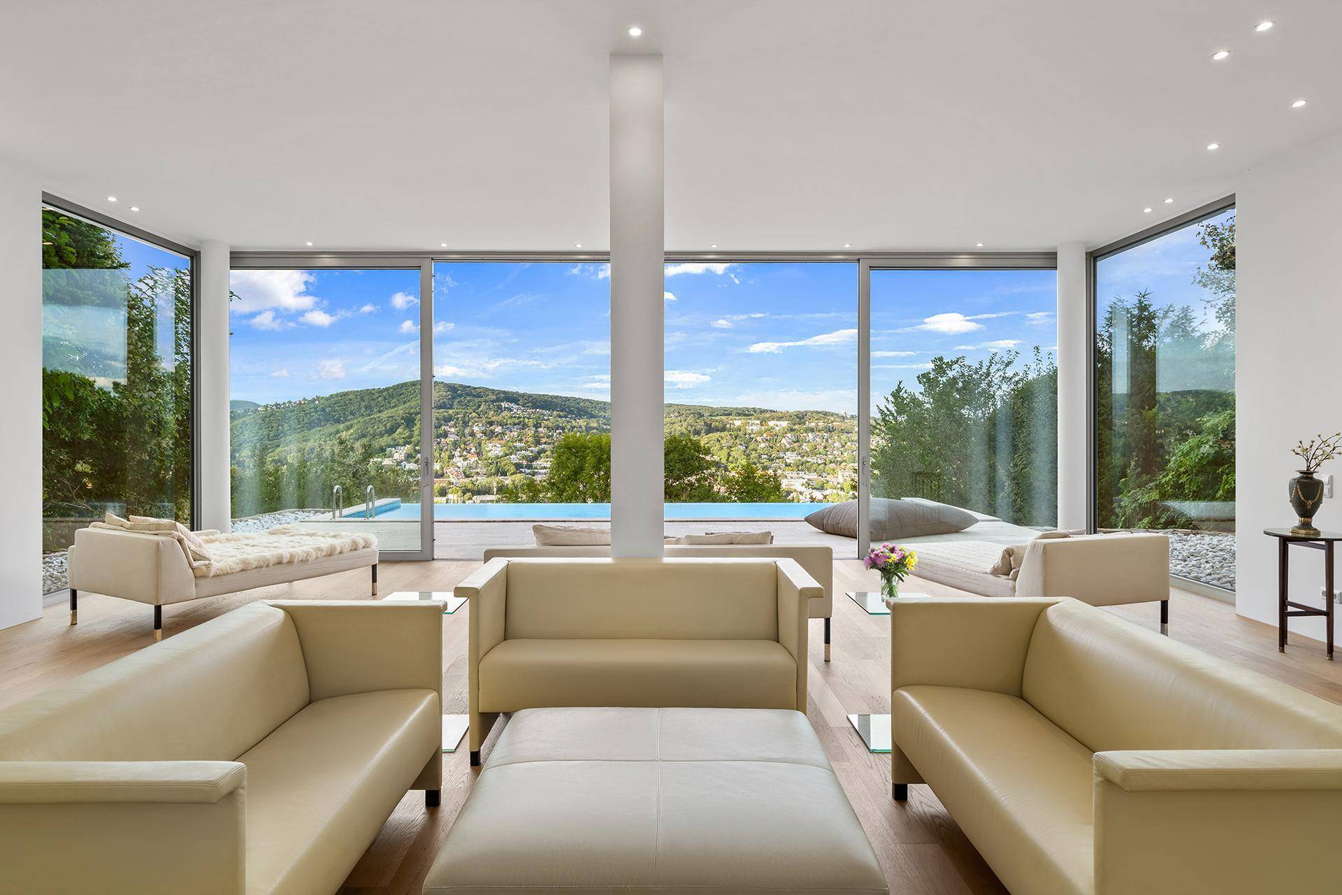 Helles Wohnzimmer mit großen Glasfronten, die einen direkten Blick auf den Pool und die umliegende Landschaft ermöglichen.