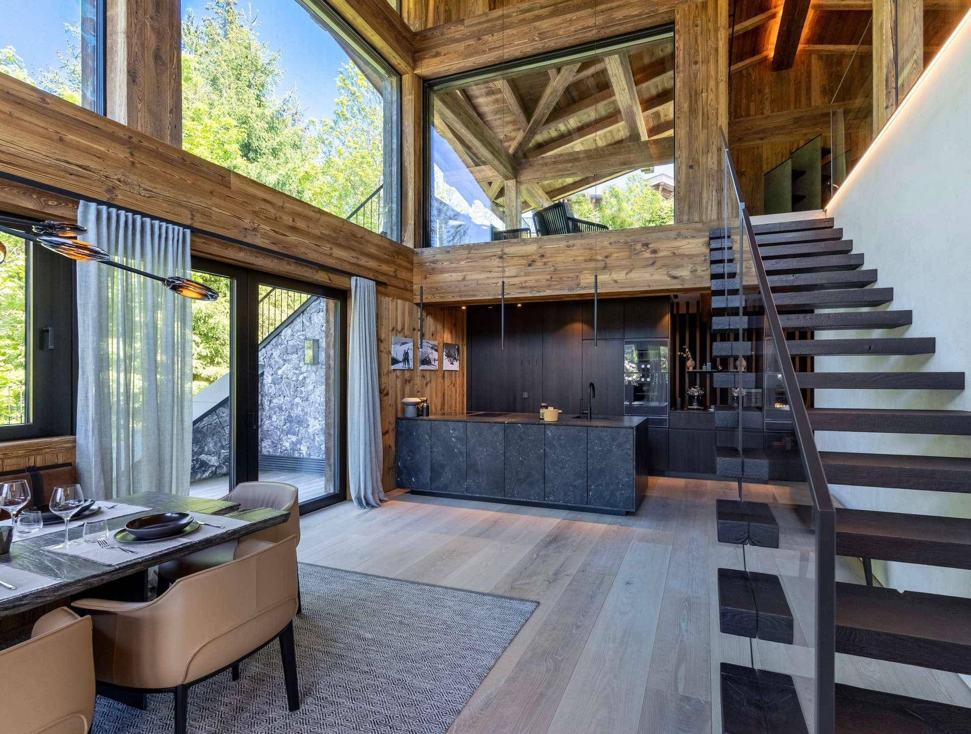 Moderne offene Küche mit dunklen Steinplatten und integriertem Essbereich in einem Holzchalet.