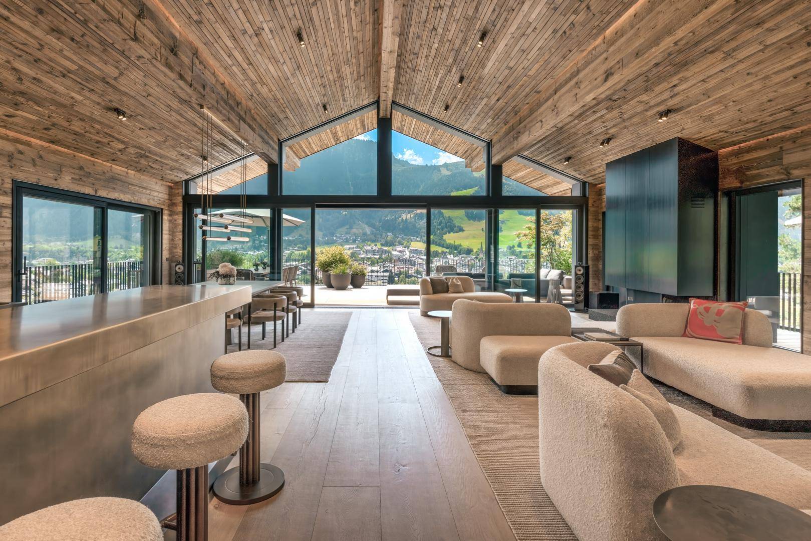 Offener Wohnbereich mit Bar, bequemen Sofas und raumhohen Fenstern mit beeindruckendem Bergpanorama.