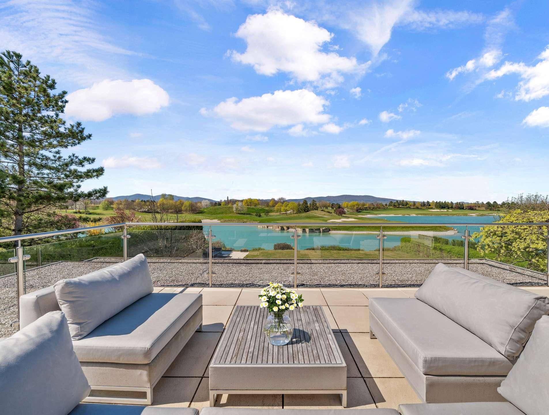 Große Dachterrasse mit Lounge-Möbeln und Panoramablick auf den See und die Berge.