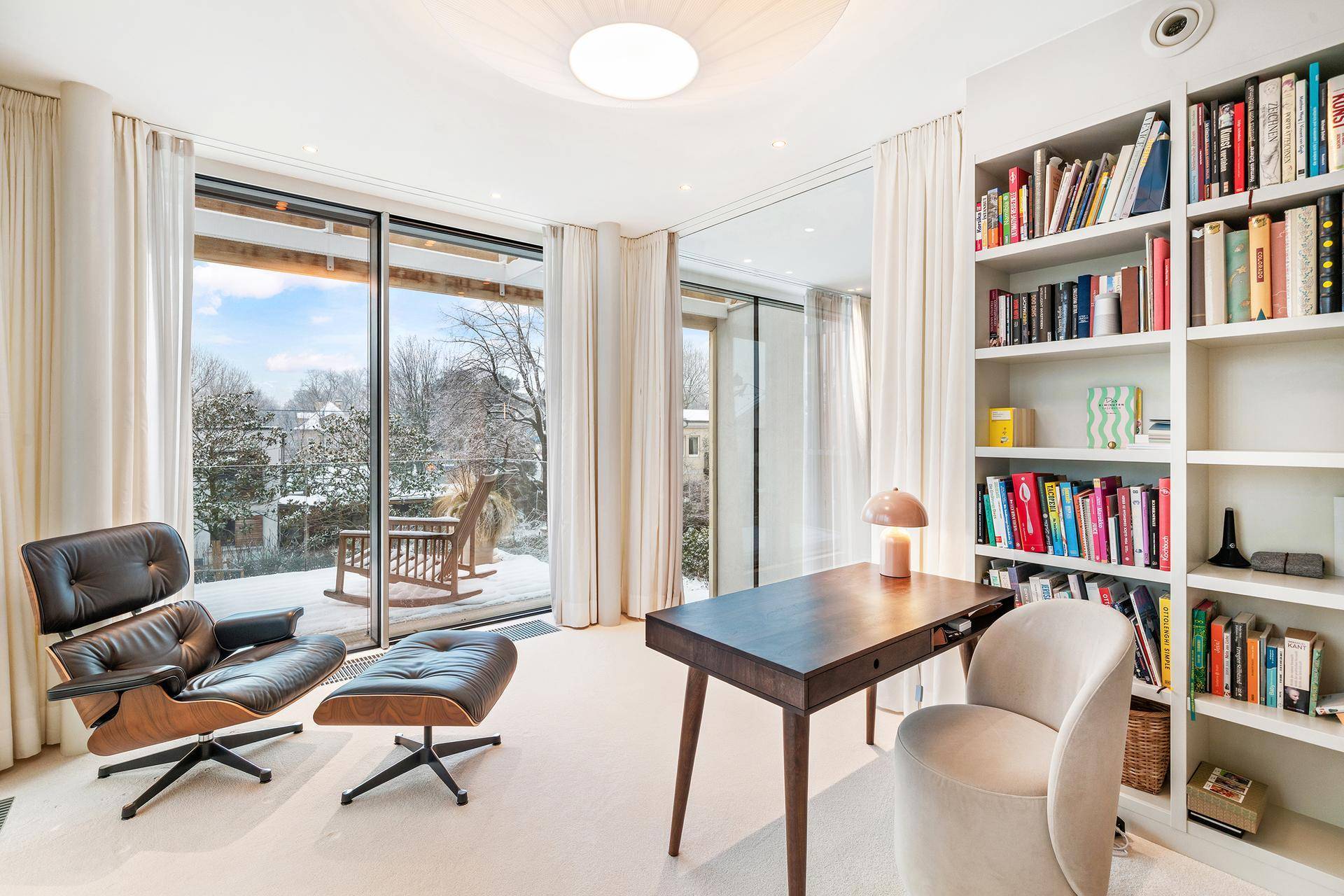 Helles Arbeitszimmer mit bodentiefen Fenstern, Blick ins Grüne und integriertem Bücherregal.
