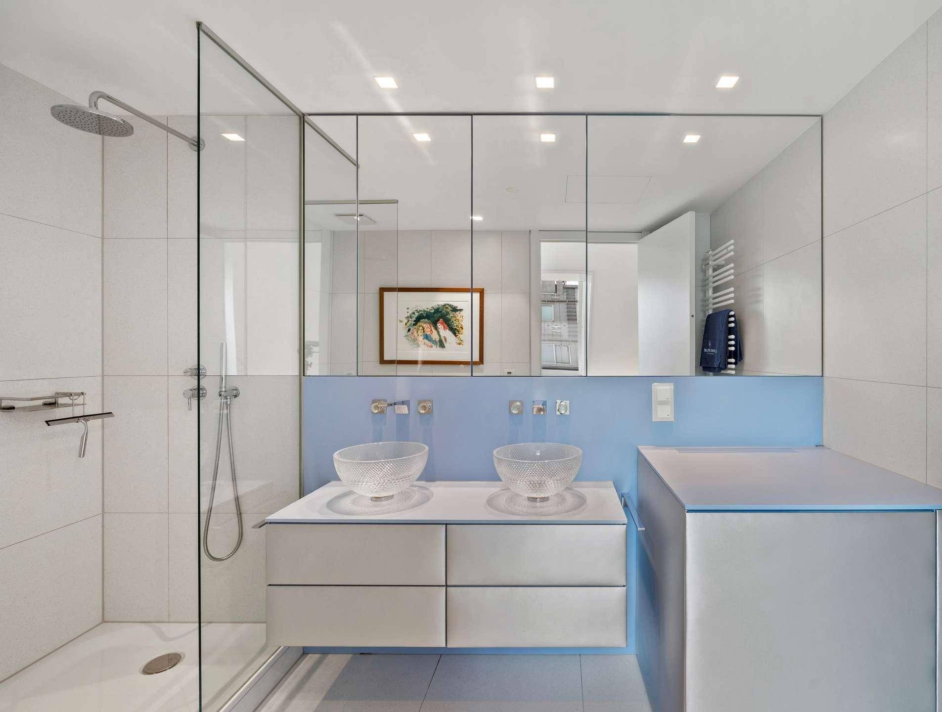 Modernes Badezimmer mit Doppelwaschbecken, begehbarer Dusche und hellen Fliesen.