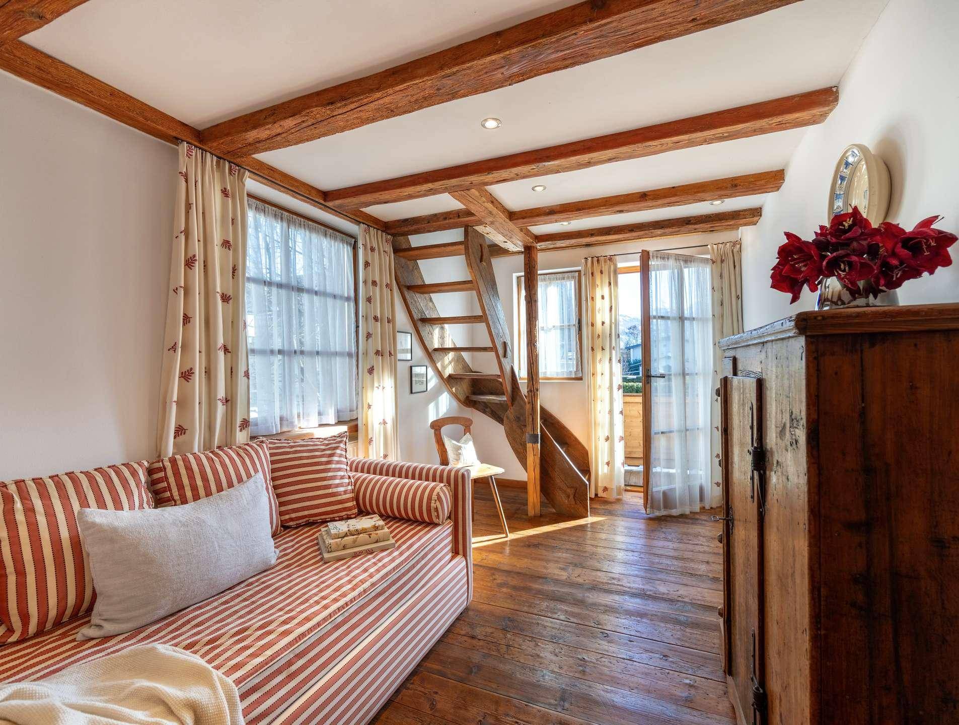Schlafzimmer mit sichtbaren Holzbalken, Dielenboden und direktem Zugang zum Balkon.