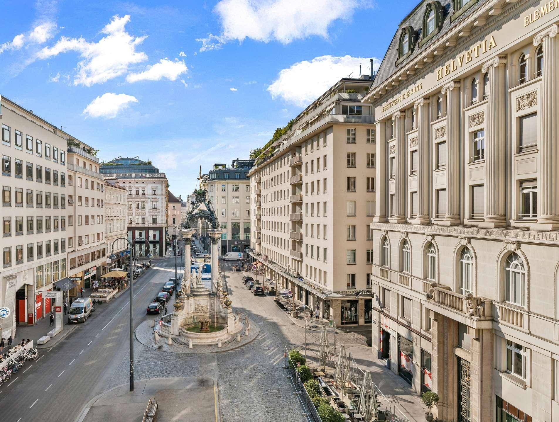 Panoramablick auf eine belebte Stadtstraße mit historischen Gebäuden und einem Denkmal.