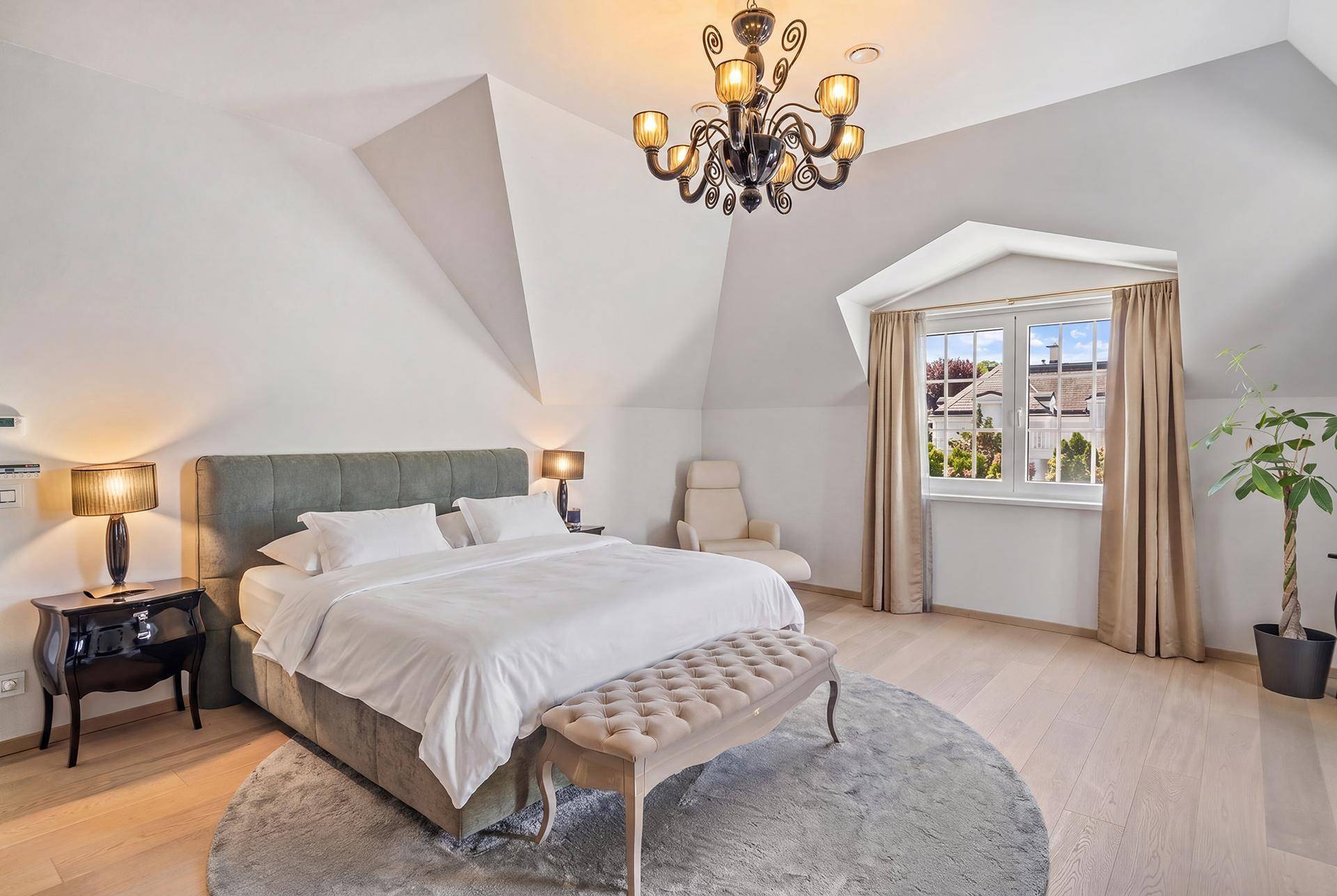 Helles Schlafzimmer im Dachgeschoss mit schrägen Decken, Holzboden und großem Bett.