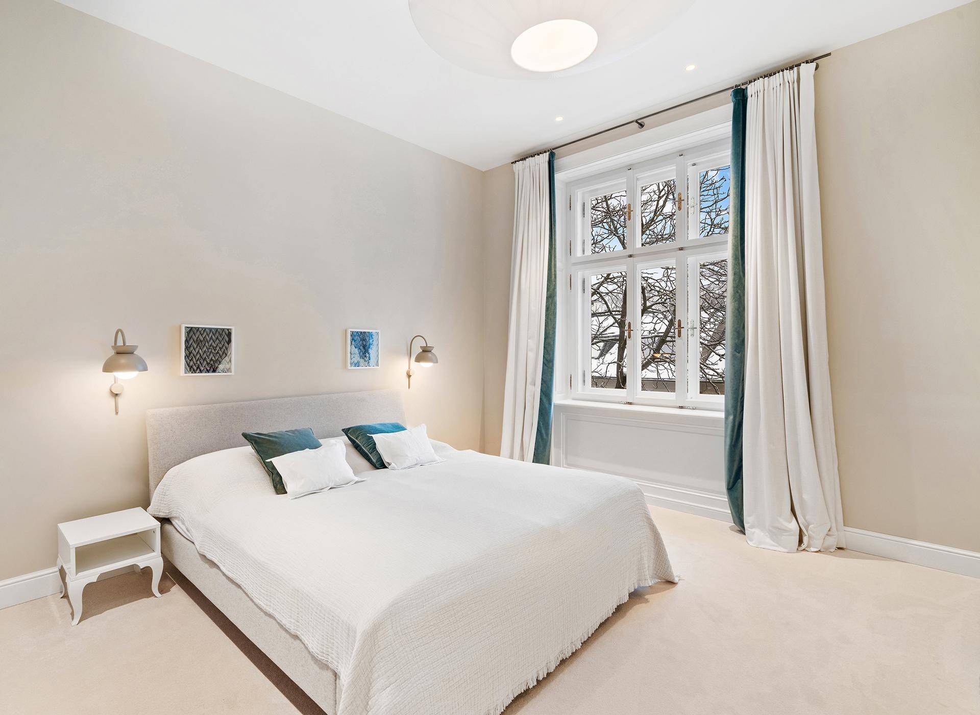 Gemütliches Schlafzimmer mit hellem Teppichboden, großem Fenster und bequemen Doppelbett.