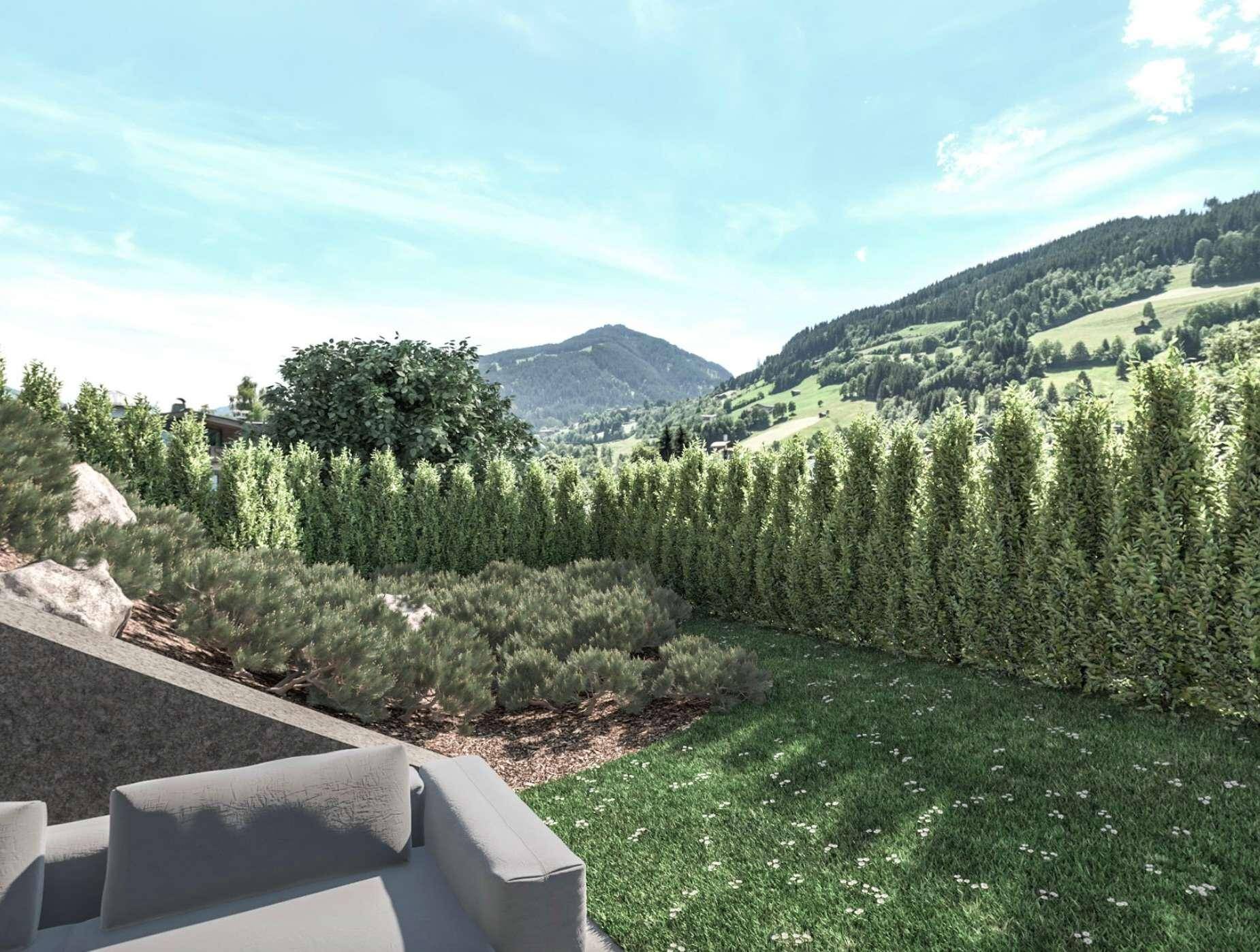 Gepflegter Gartenbereich mit Rasenfläche, hohen Hecken und einem malerischen Bergblick in der Ferne.