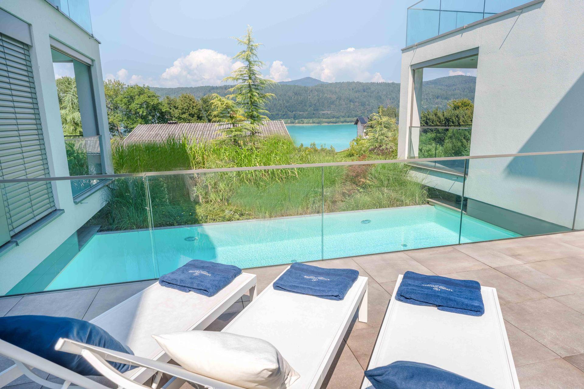 Sonnige Terrasse mit Liegestühlen und einem privaten Pool mit Seeblick.