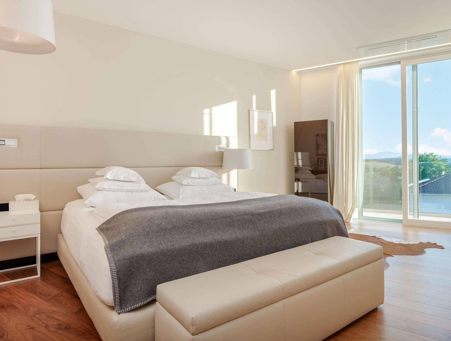 Helles Schlafzimmer mit Doppelbett, Holzboden und direktem Zugang zu einem Balkon.