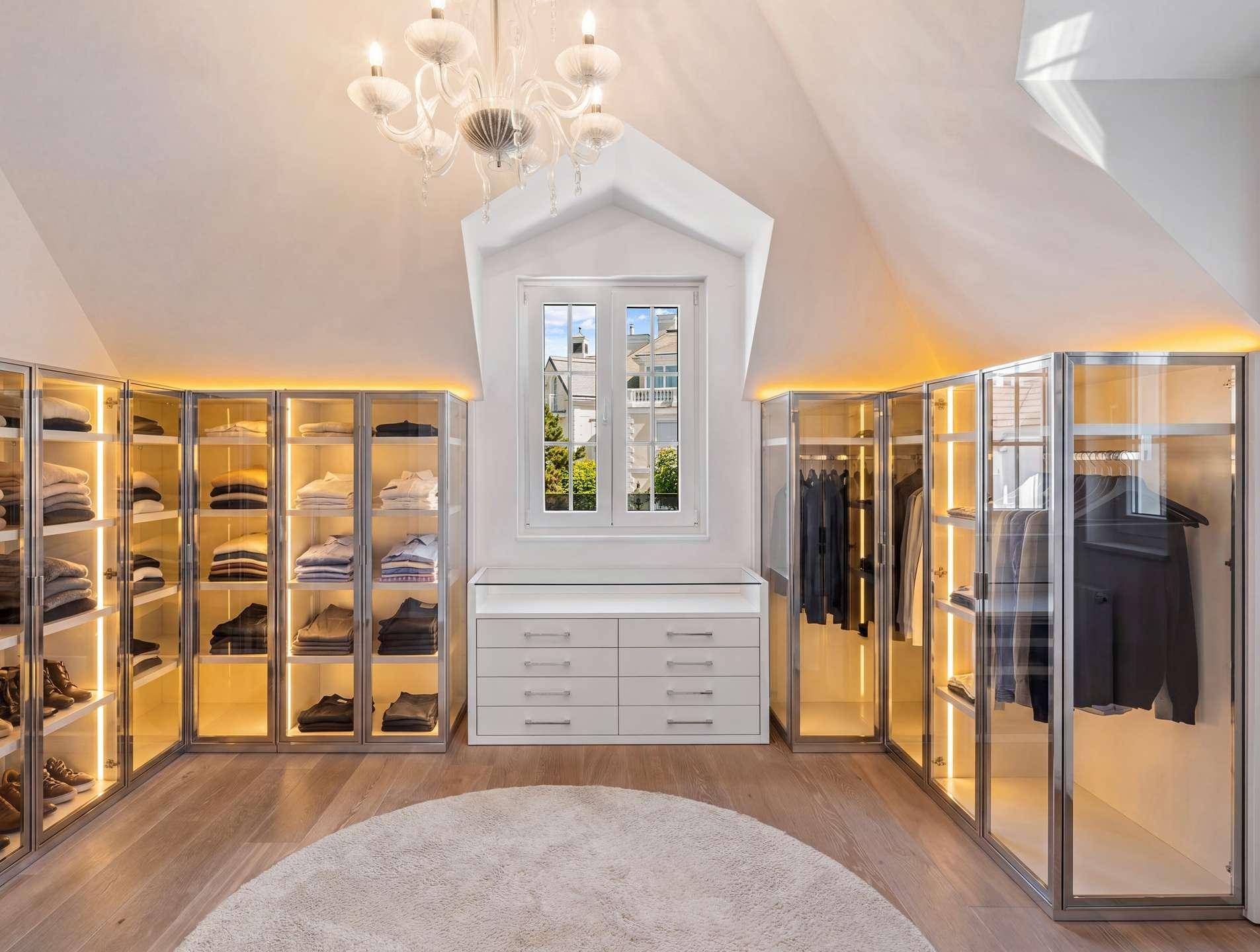 Geräumiger begehbarer Kleiderschrank mit integrierter Beleuchtung und viel Stauraum.