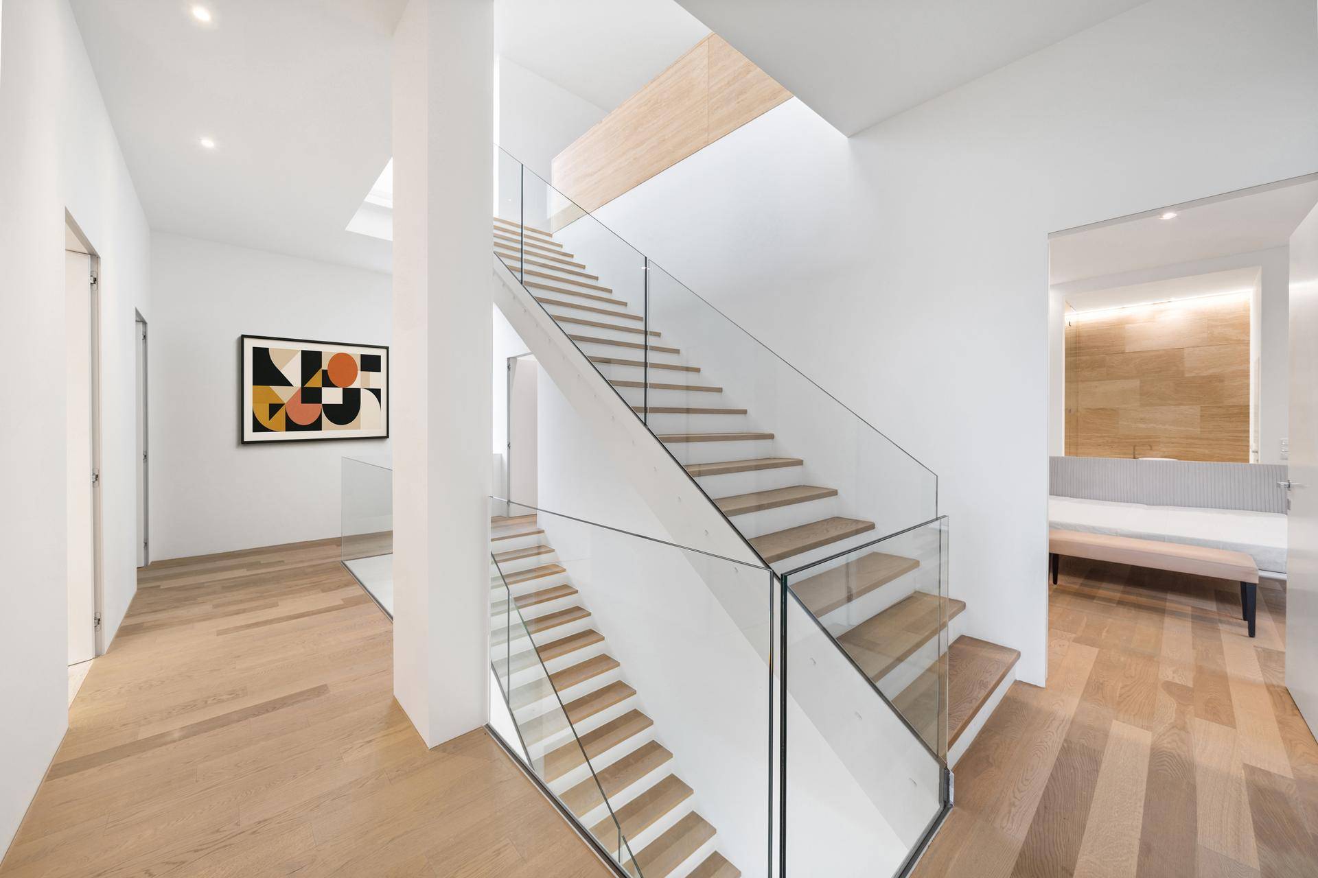 Moderne Treppe mit Holzstufen und Glasgeländer, die die verschiedenen Ebenen des Hauses elegant verbindet.
