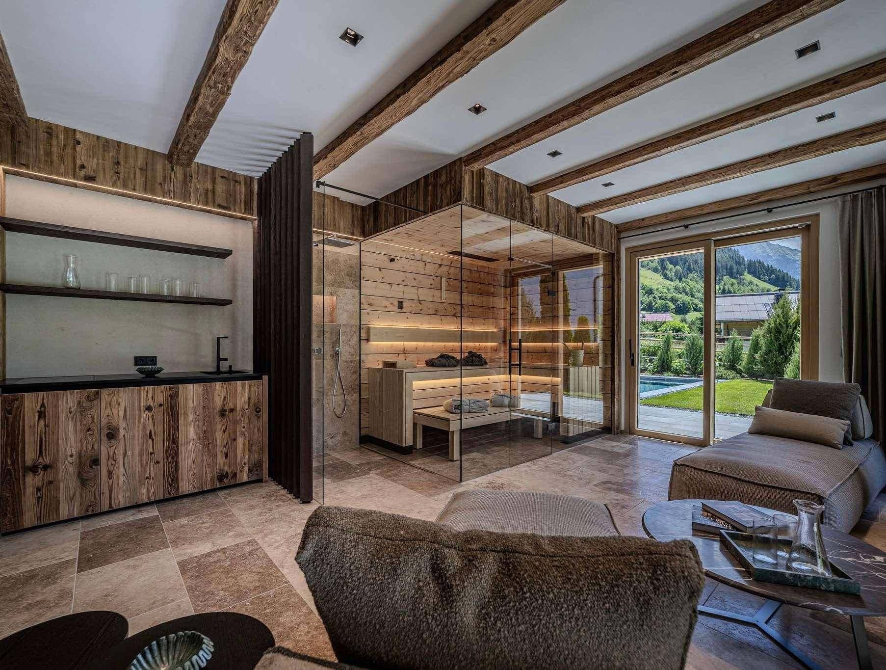 Exklusiver Wellnessbereich mit Sauna, Liegefläche und Blick ins Grüne.