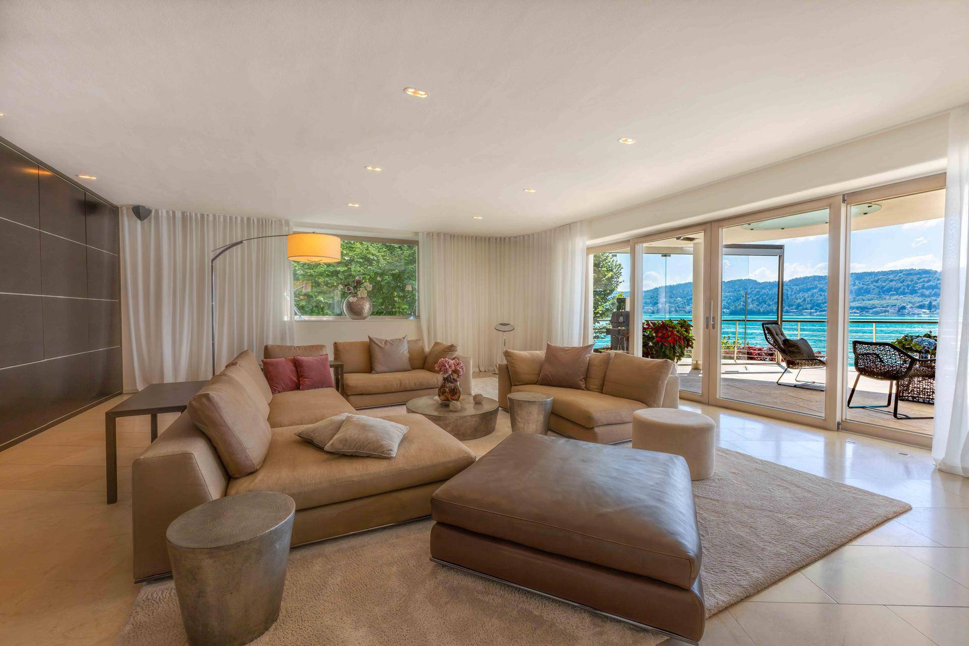 Helles Wohnzimmer mit bequemer Sitzecke, modernen Möbeln und direktem Zugang zur Terrasse mit Seeblick.