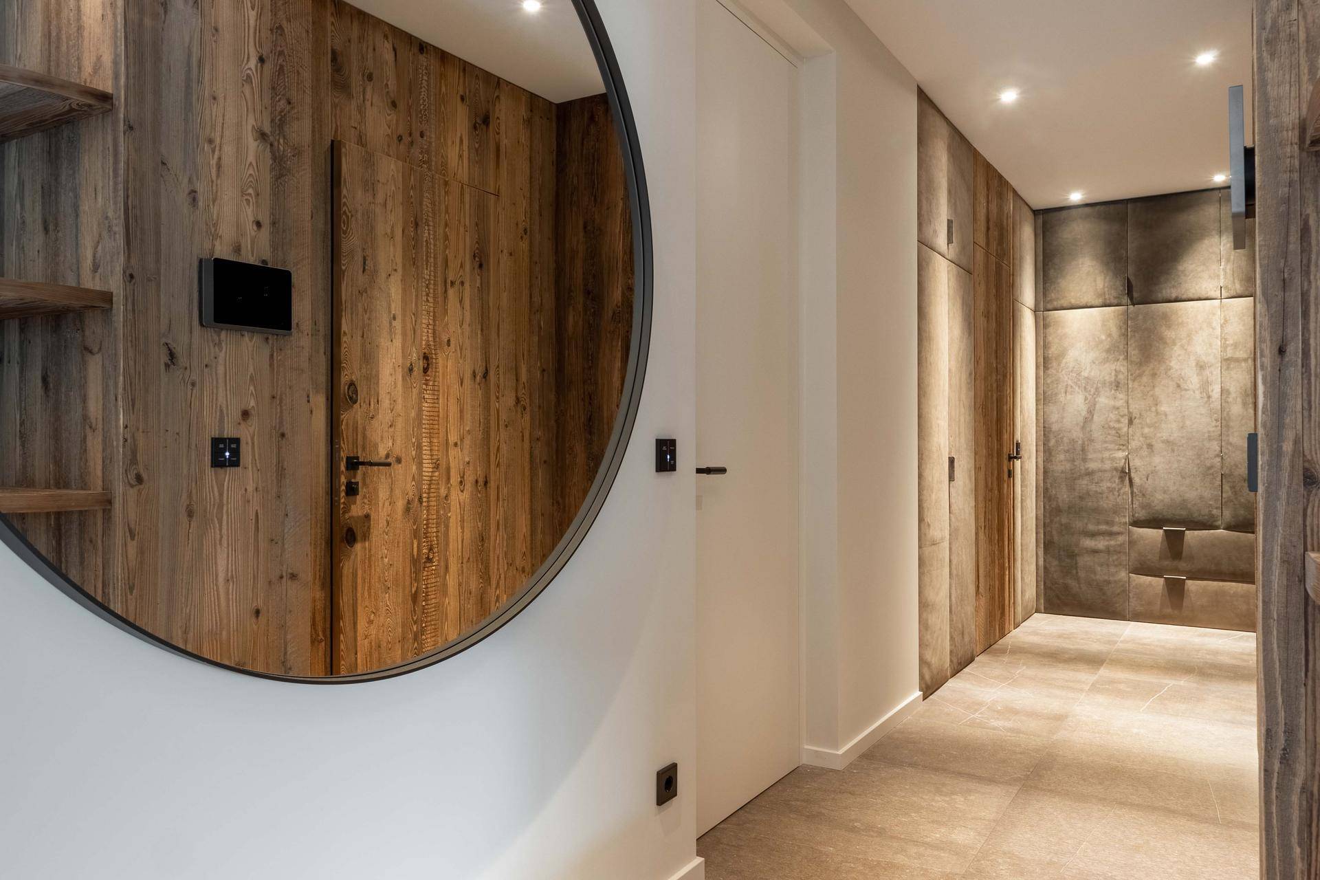 Moderner Flur mit Holzwänden, großem Rundspiegel und integrierten Schränken.