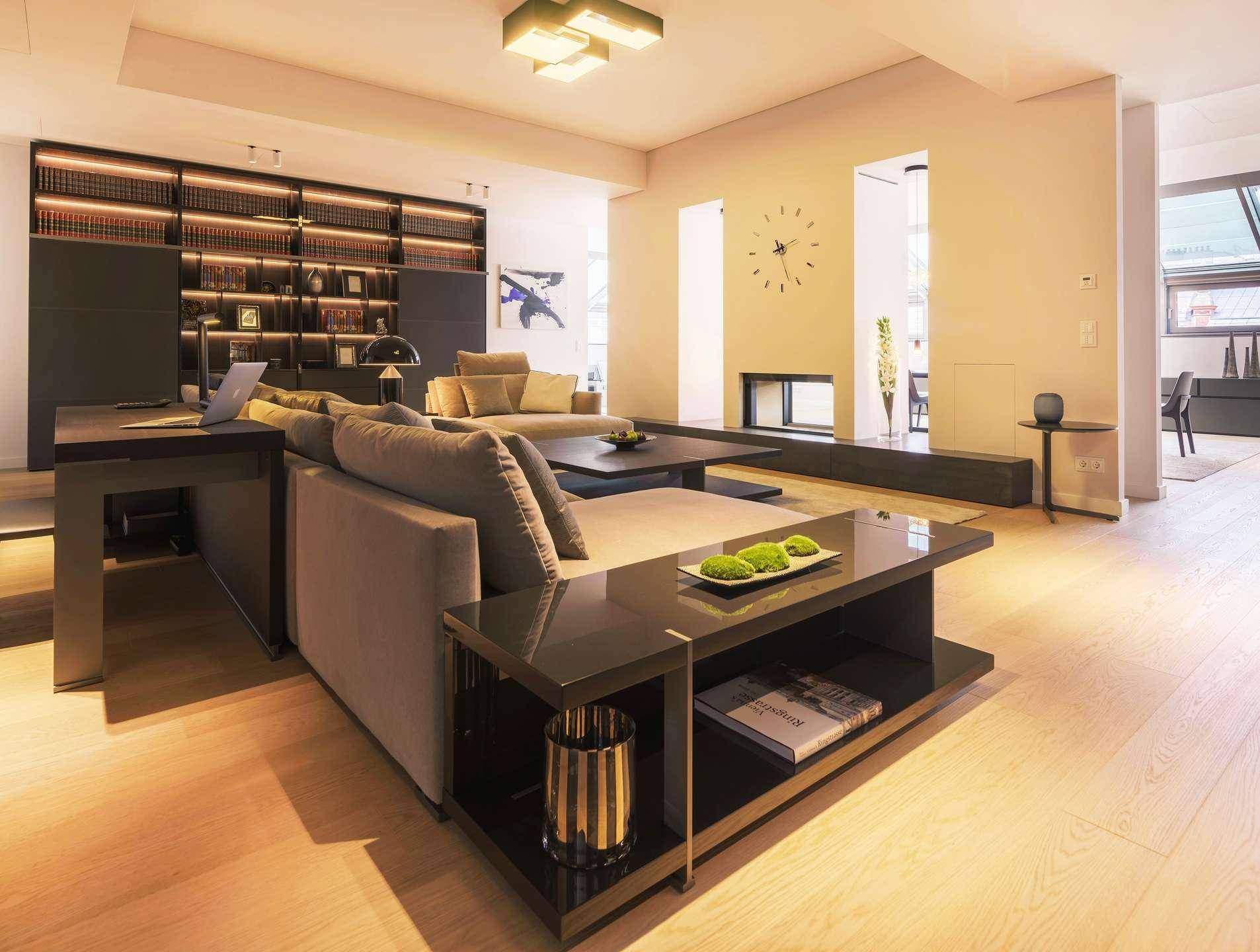 Geräumiges Wohnzimmer mit bequemen Sofas, Holzboden und einer eleganten, beleuchteten Bücherwand.