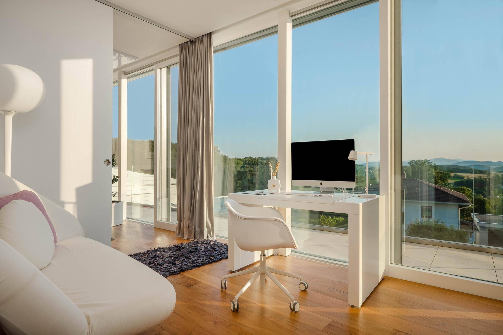 Heller Arbeitsbereich mit modernem Schreibtisch und Stuhl, direkt an raumhohen Fenstern mit Panoramablick.