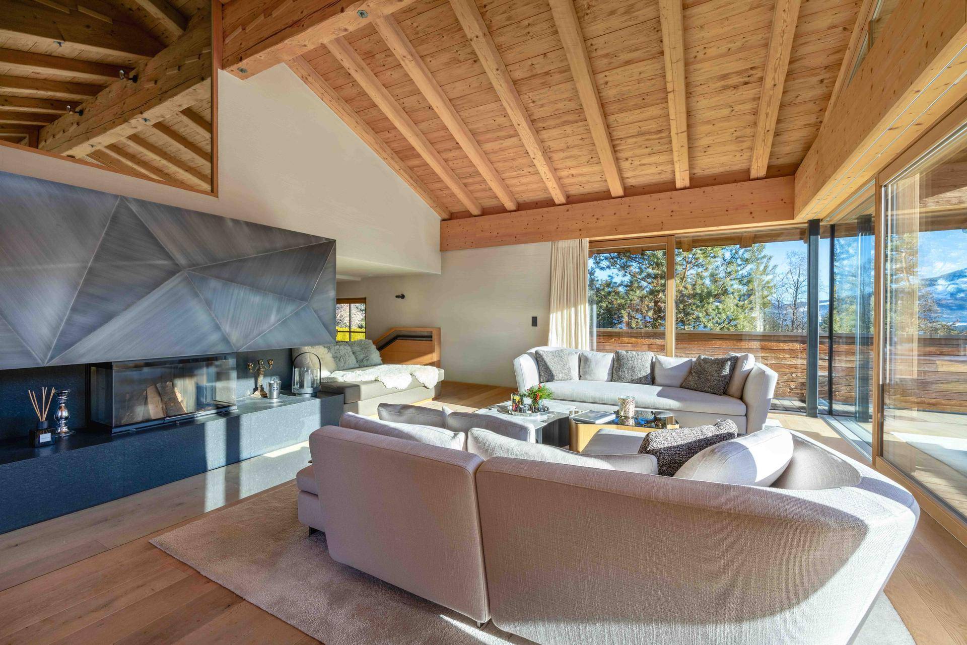 Geräumiges Wohnzimmer mit modernem Kamin, Holzbalkendecke und Zugang zur Terrasse.