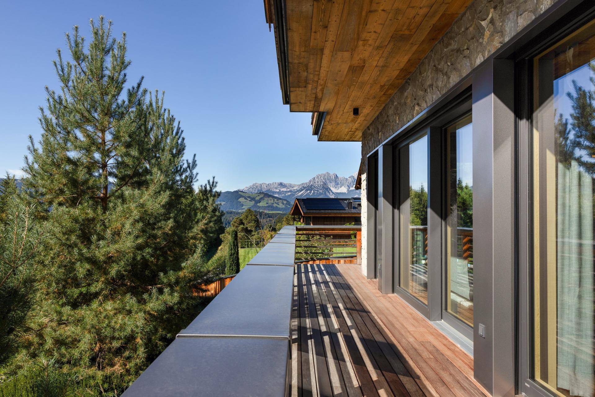 Geräumiger Balkon mit Holzboden und atemberaubendem Blick auf die umliegende Berglandschaft.
