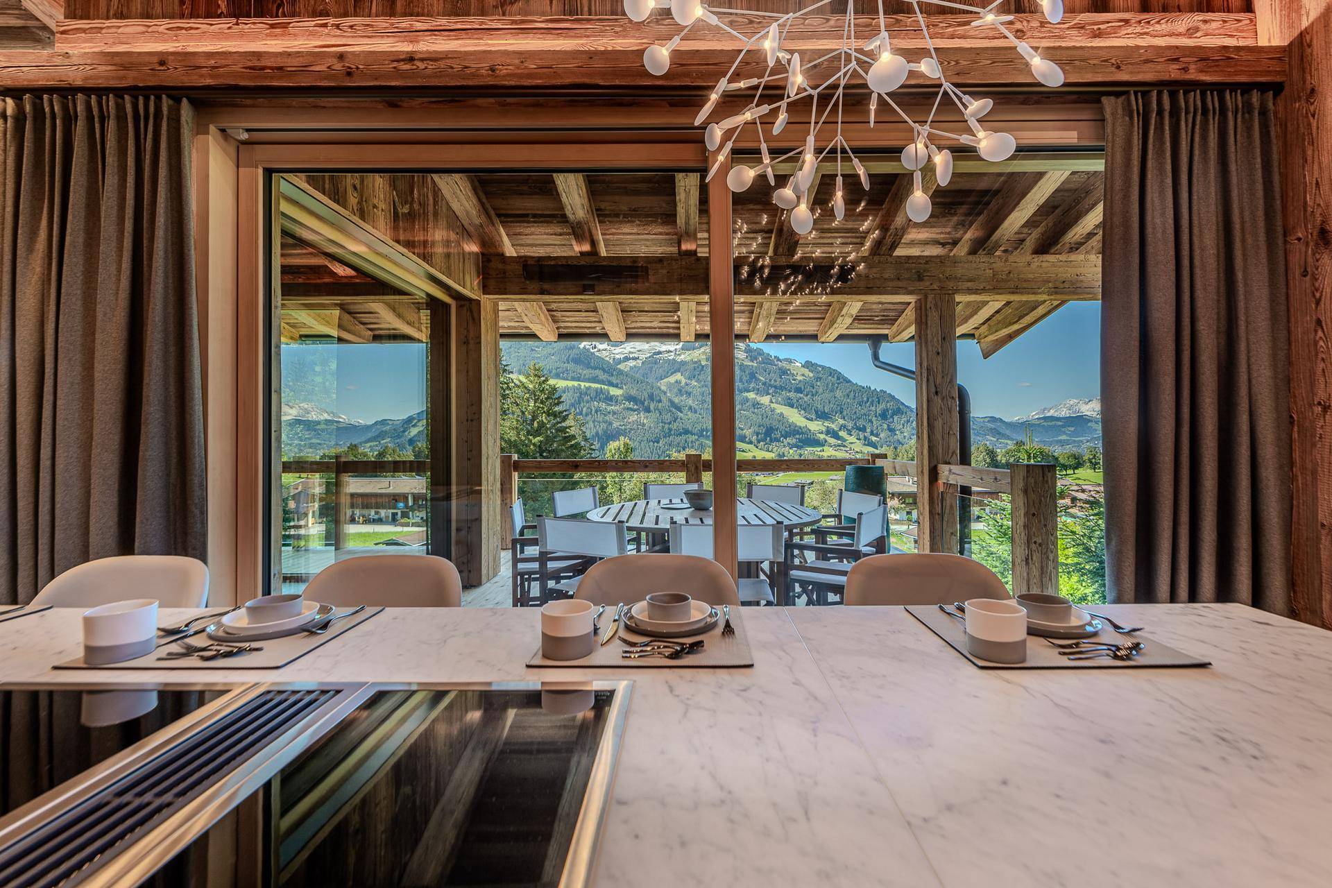 Moderne Küche mit Kochinsel, Marmorarbeitsplatte und direktem Zugang zur Terrasse mit Bergblick.