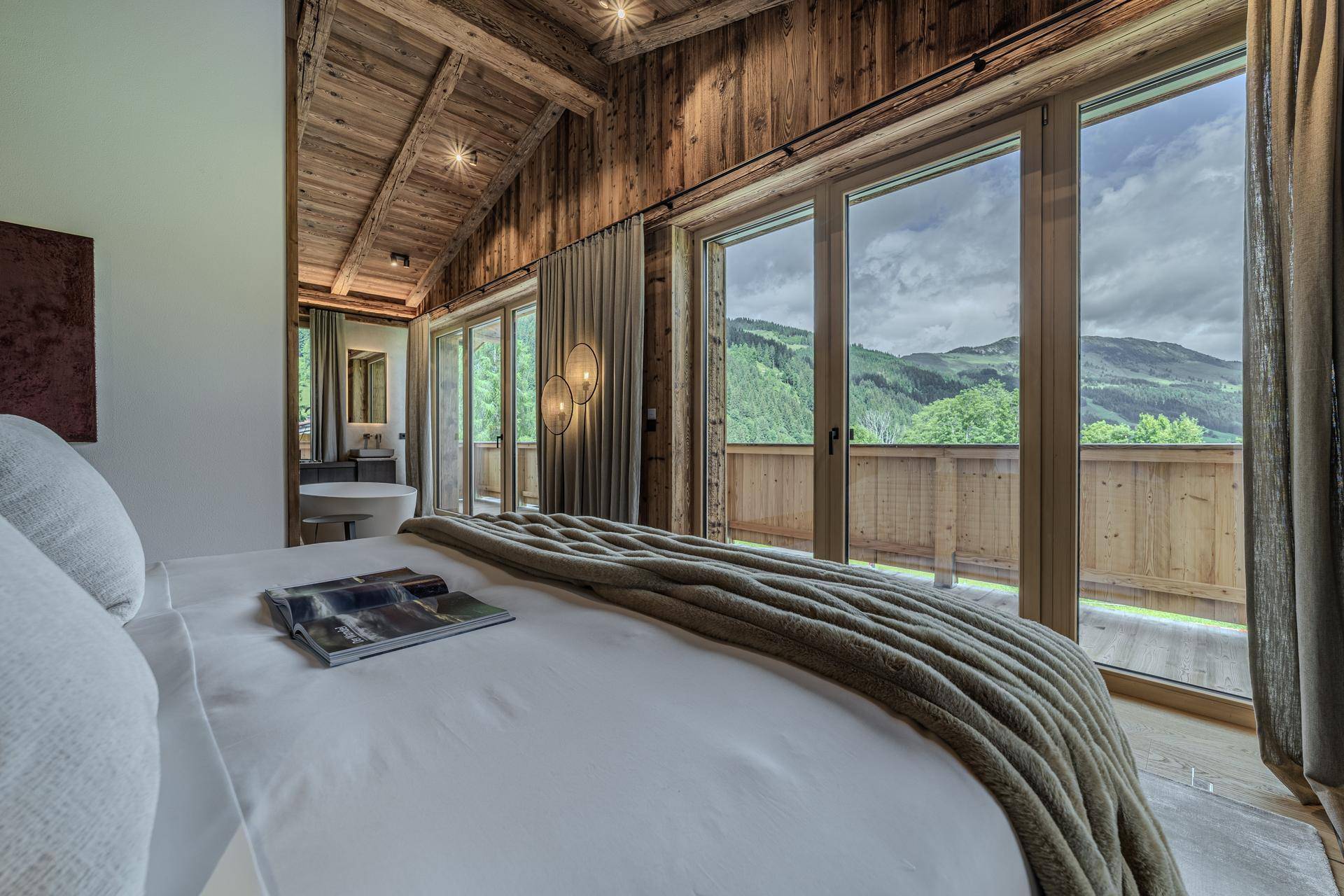 Helles Schlafzimmer mit Balkonzugang, Panoramablick auf die Berge und Holzelementen.
