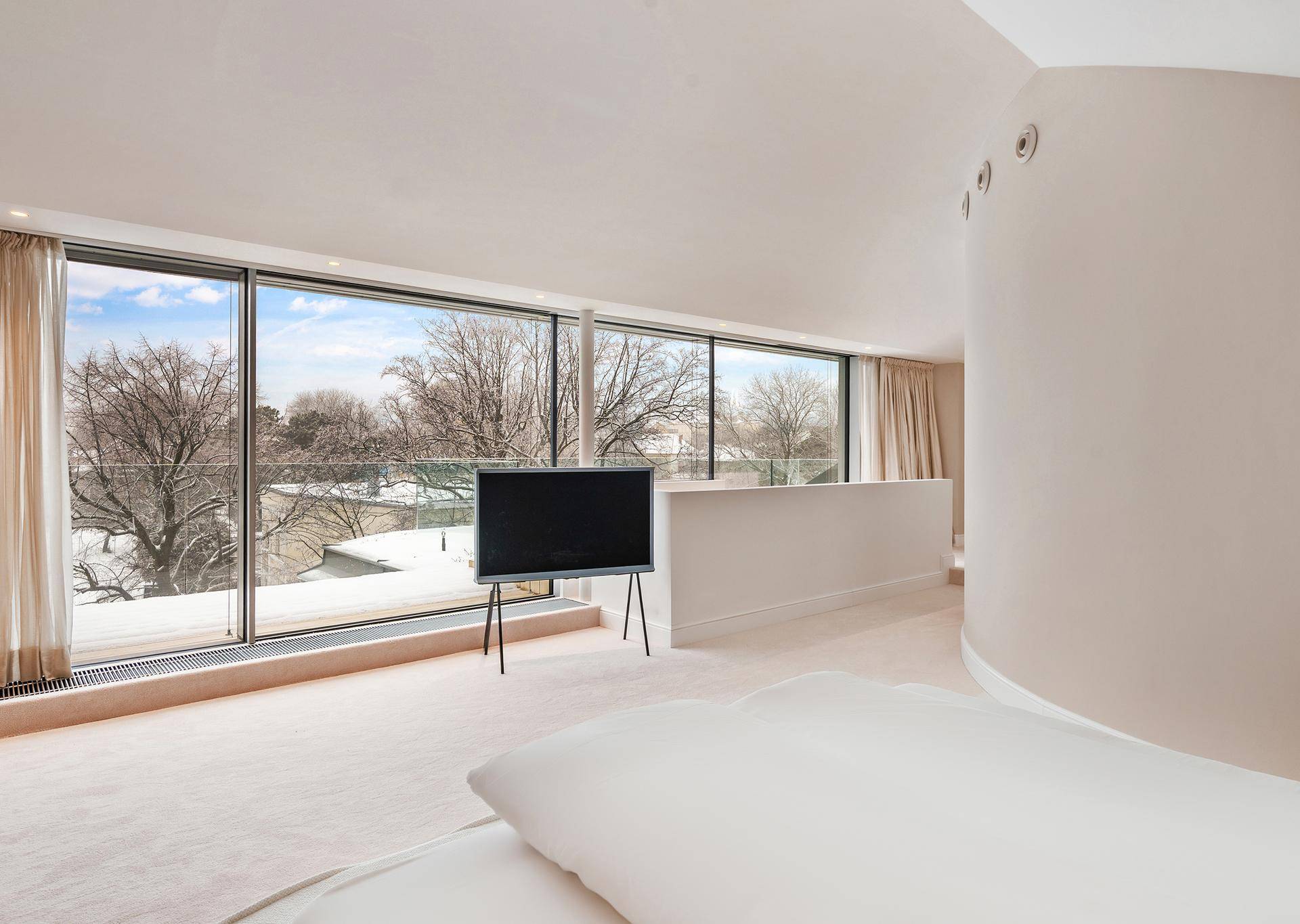 Geräumiges Schlafzimmer mit bodentiefen Fenstern, weitem Ausblick und hellem Teppichboden.