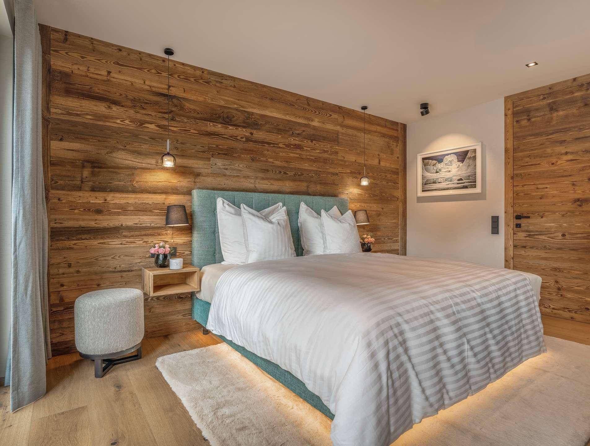 Gemütliches Schlafzimmer mit Holzwandverkleidung, Holzboden und indirekter Beleuchtung für warme Atmosphäre.