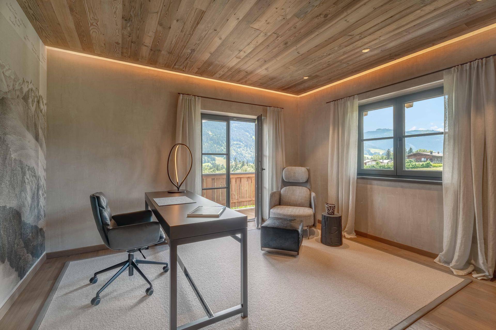 Ruhiges Arbeitszimmer mit Holzwänden, Schreibtisch und weitem Blick auf die Berge.