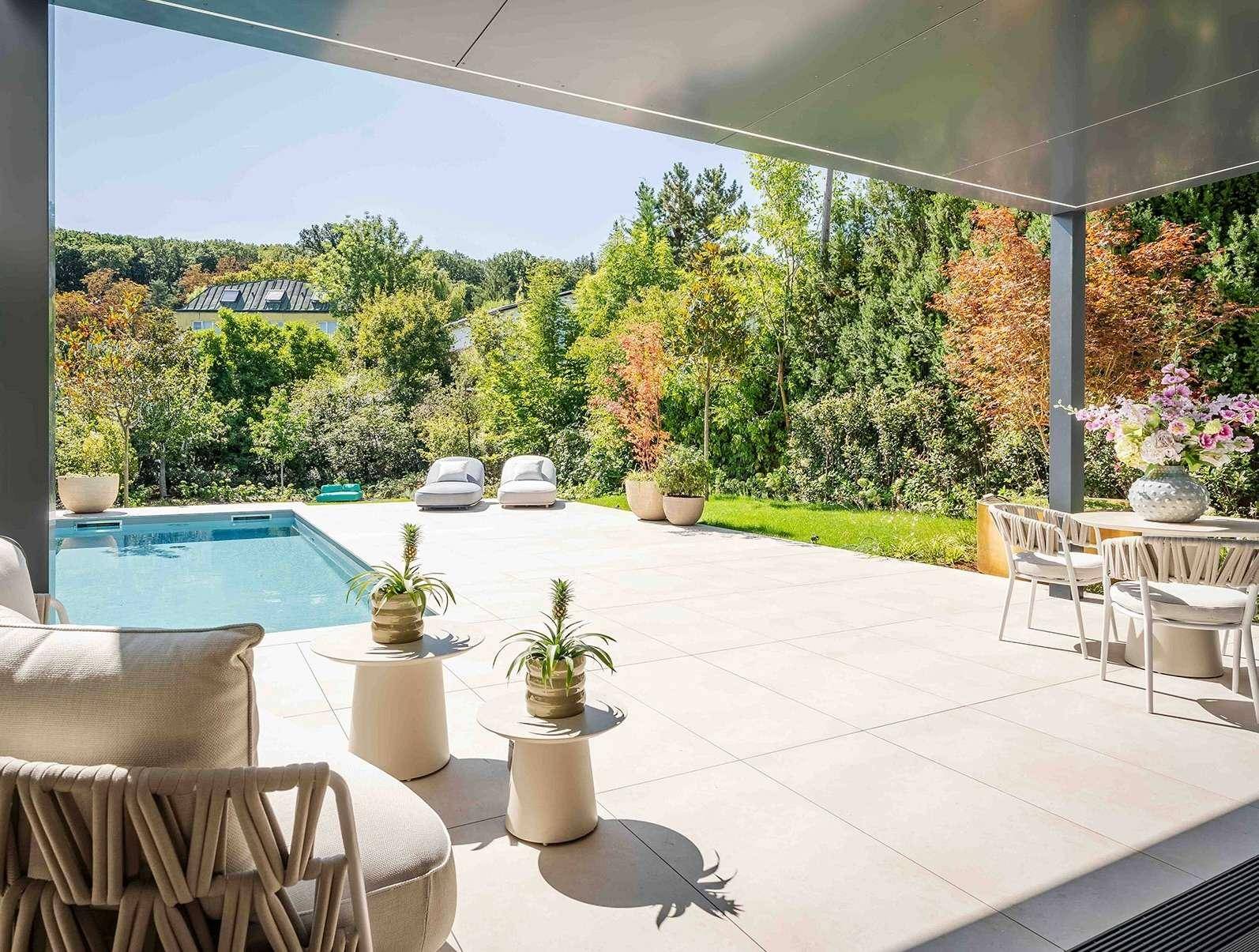 Großzügige Terrasse mit Swimmingpool, Liegestühlen und Essbereich, umgeben von üppigem Grün.