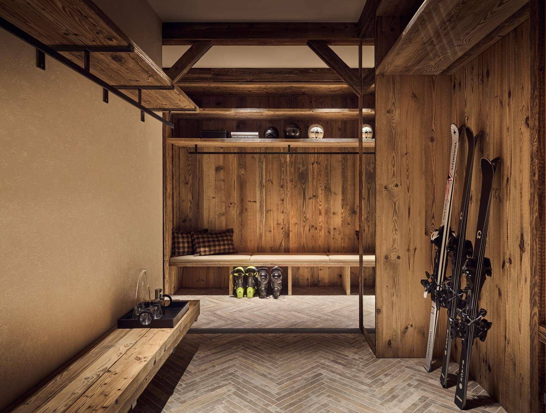 Praktischer Skiraum mit Holzbänken, Ablagen und Platz für Skiausrüstung und Stiefel.