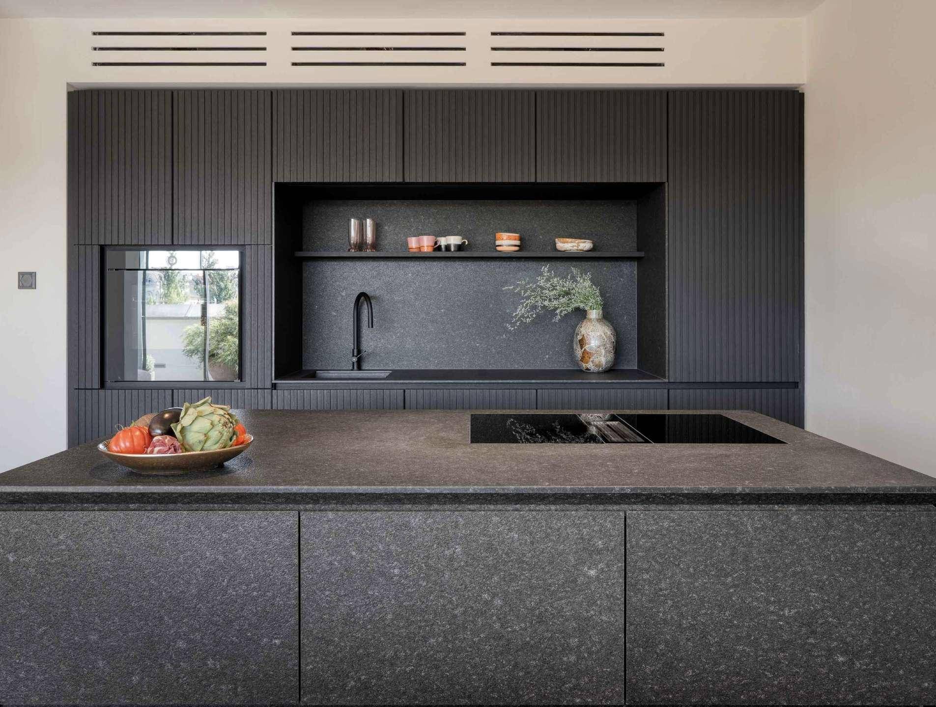 Moderne Küche mit dunklen Schränken, Kücheninsel und integriertem Induktionskochfeld.