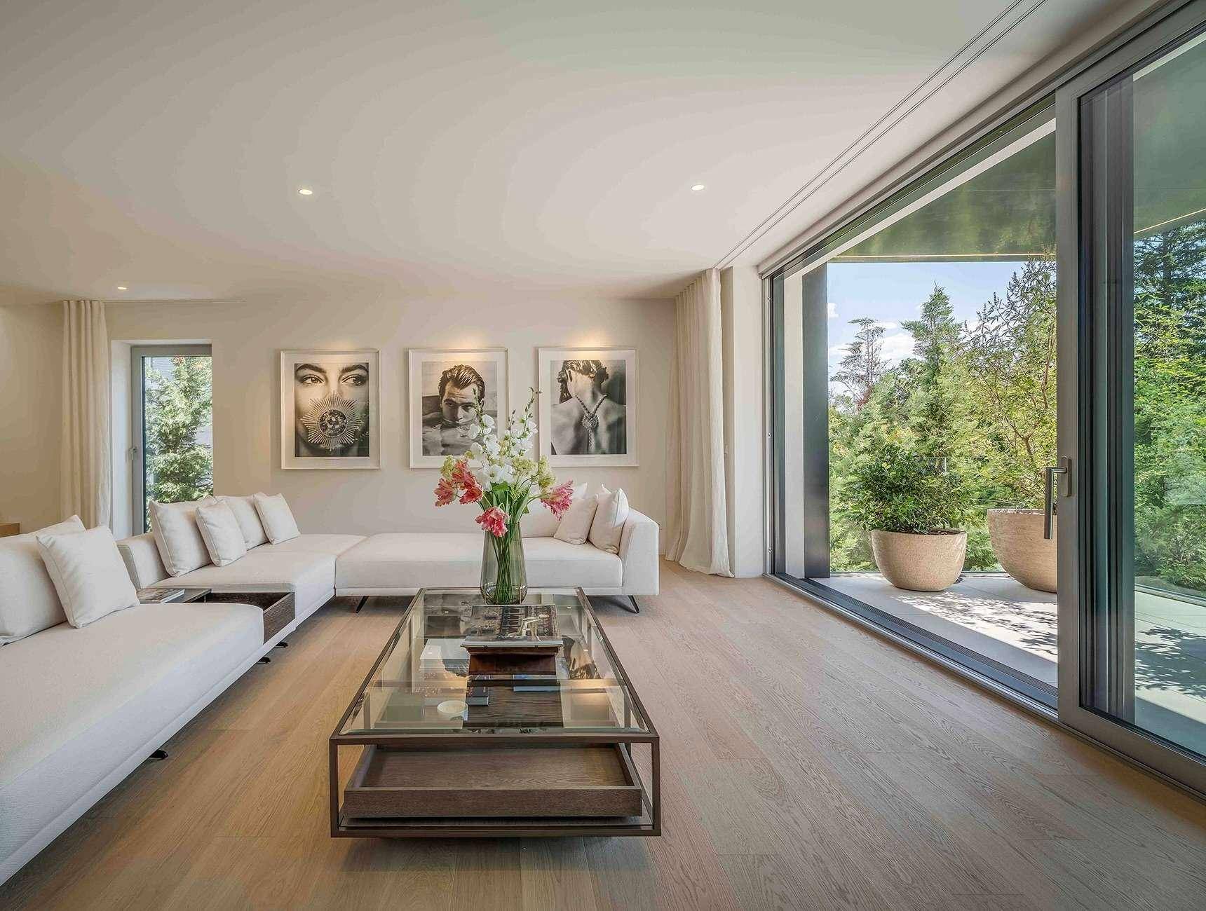 Elegantes Wohnzimmer mit bequemen Sofas, großformatigen Kunstwerken und Zugang zu einer Außenterrasse.