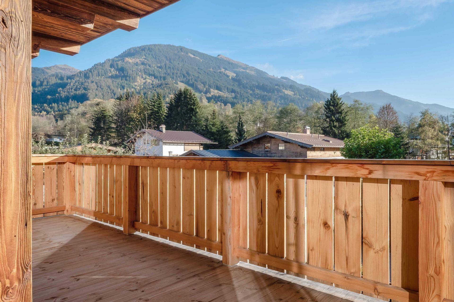 Breiter Holzbalkon mit traditionellem Geländer und weitem Blick auf die bewaldeten Berge und Täler.