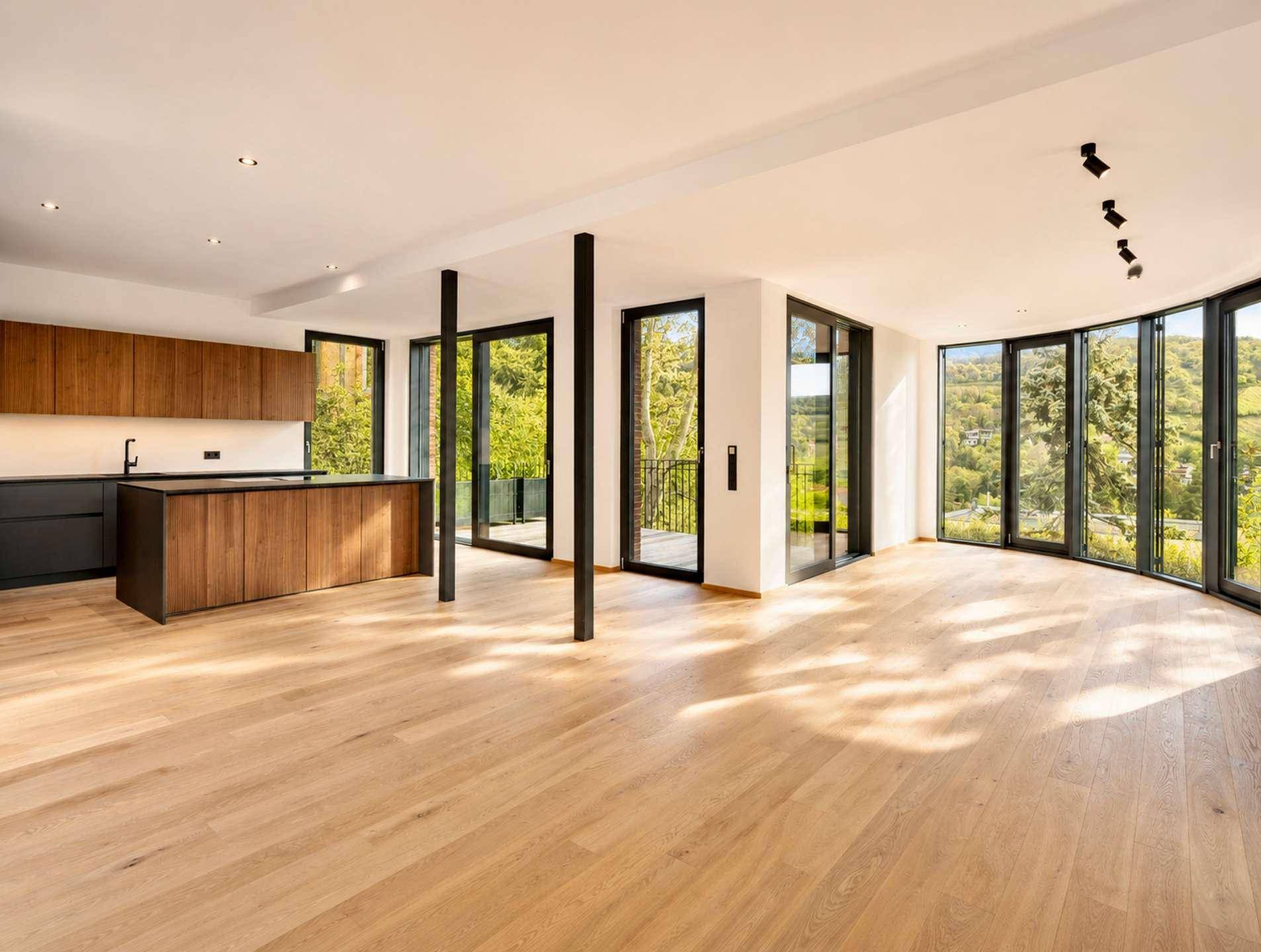 Lichtdurchfluteter offener Wohnbereich mit moderner Holzküche und Panoramablick ins Grüne durch große Fenster.