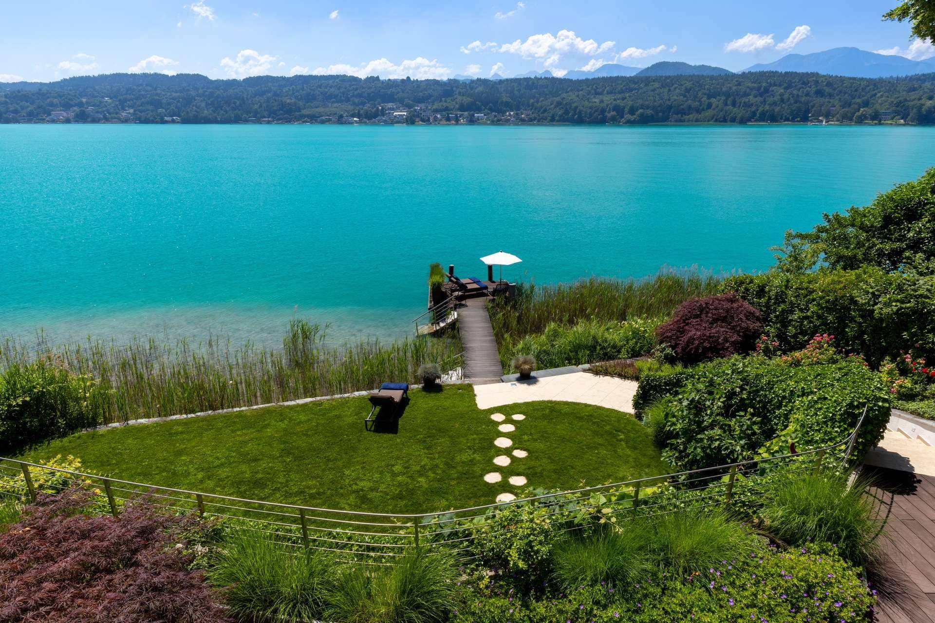 Gepflegter Garten mit direktem Zugang zu einem privaten Steg am See und malerischem Bergblick.