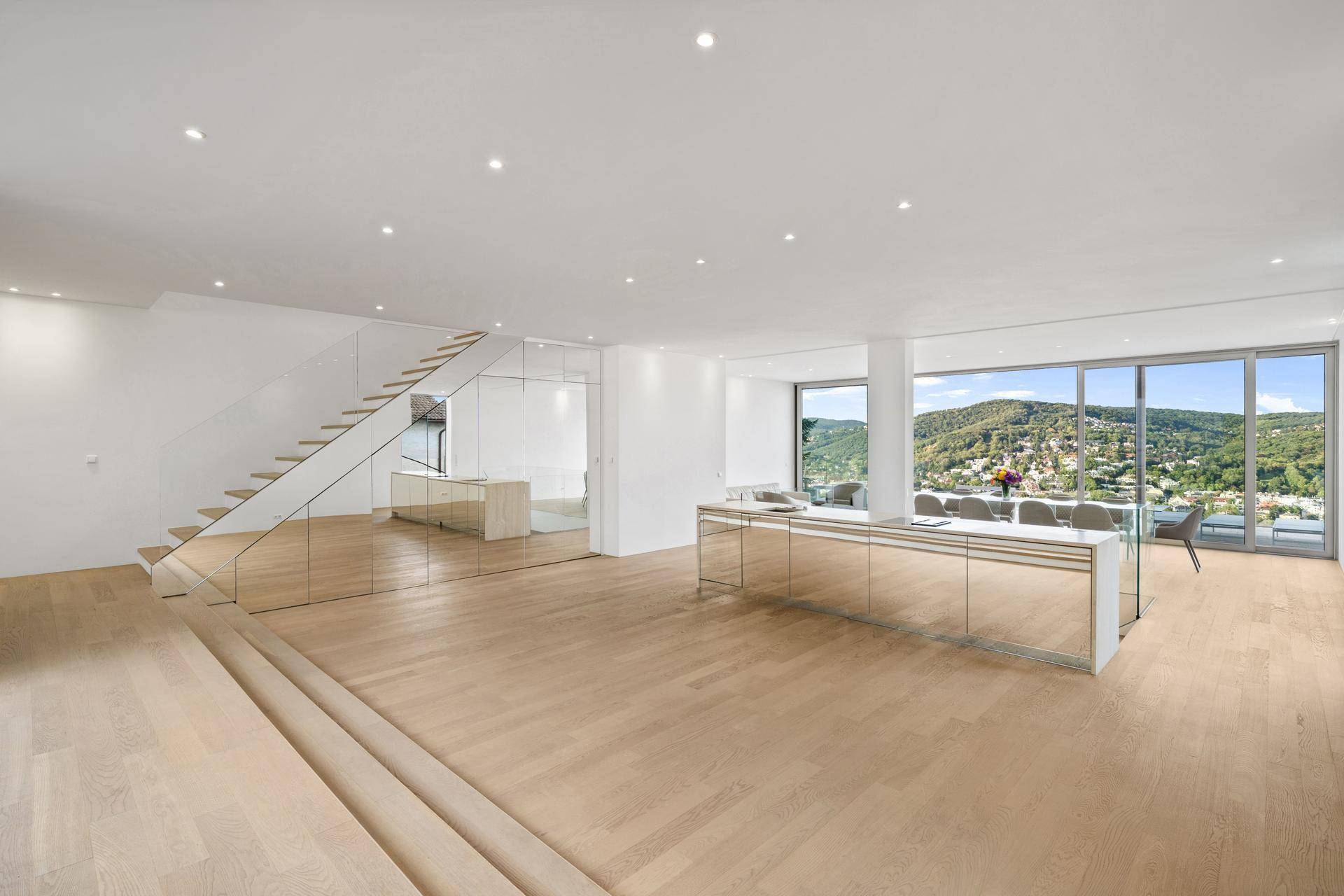 Heller, offener Wohnbereich mit moderner Treppe, verspiegelten Elementen und großen Fenstern mit Weitblick.