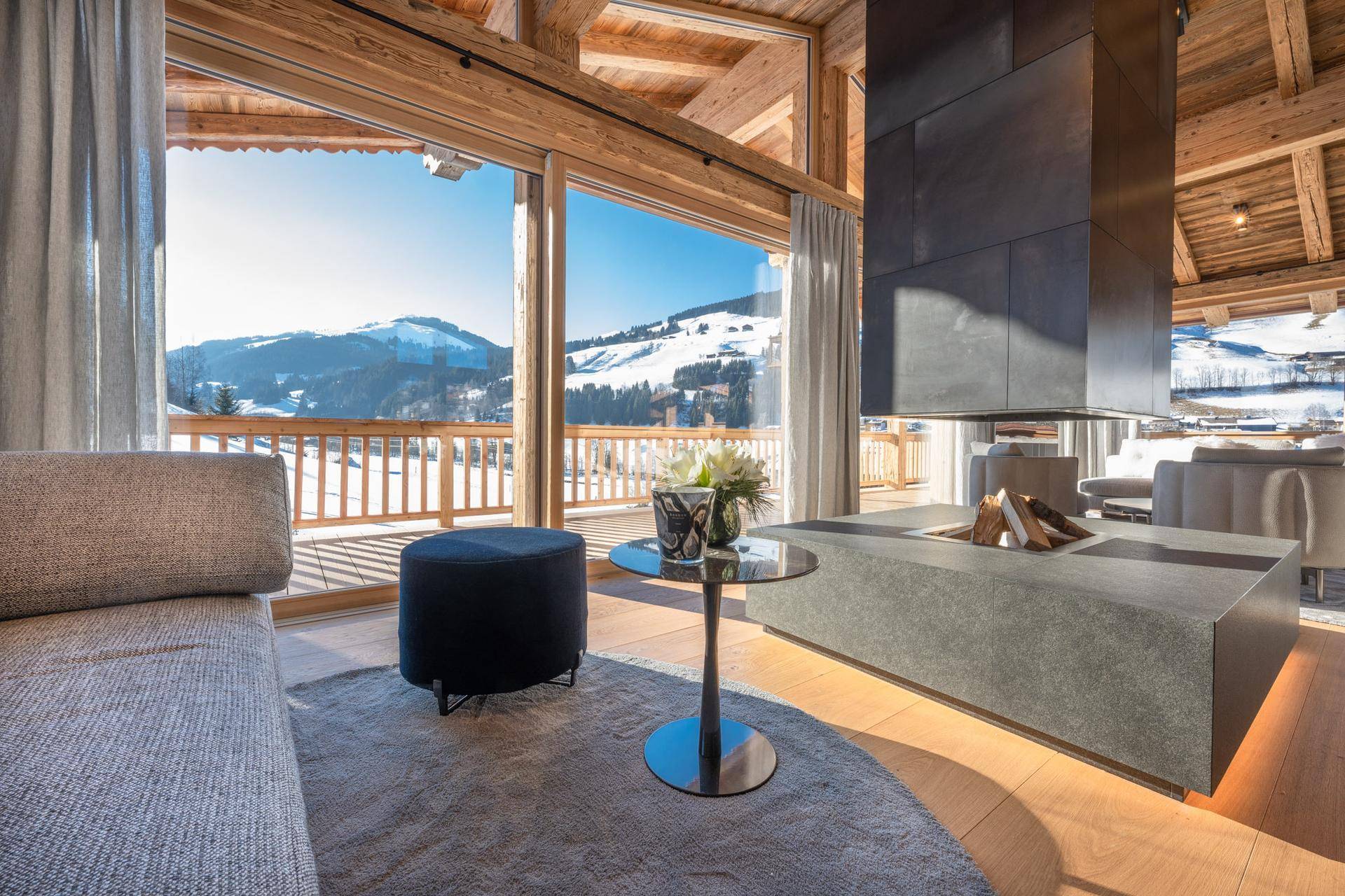 Heller Wohnbereich mit stilvollem Kamin und beeindruckendem Ausblick auf die schneebedeckten Berge.