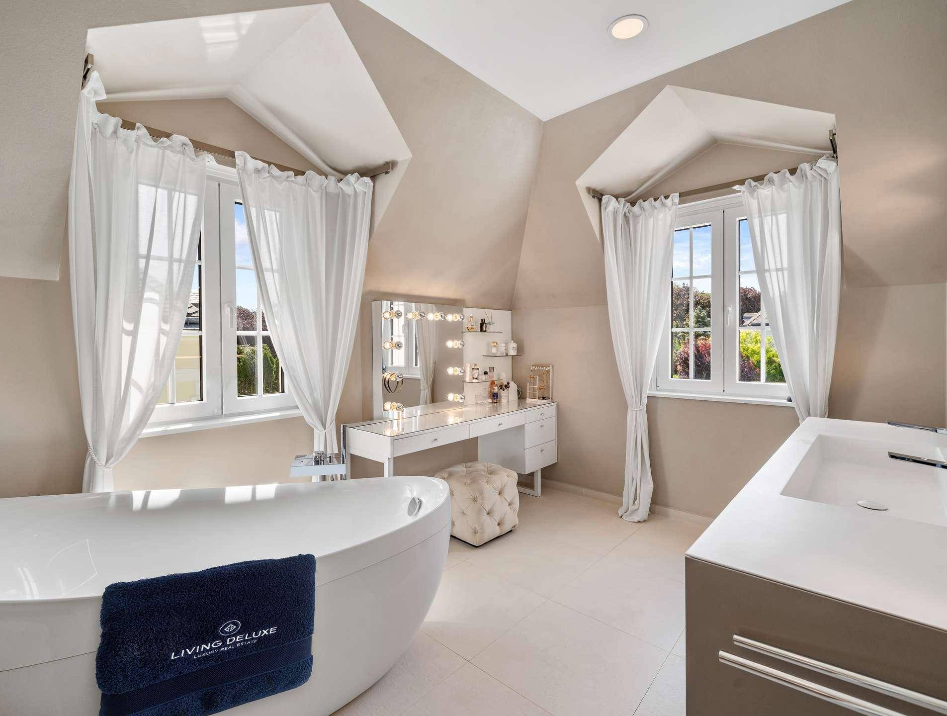 Luxuriöses Badezimmer mit freistehender Badewanne, Doppelwaschbecken und Schminktisch.