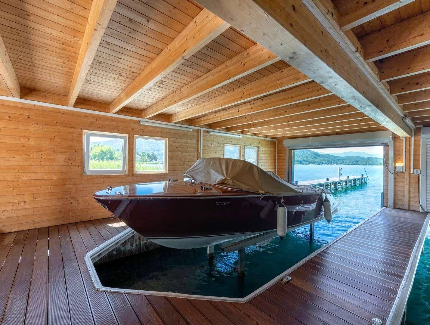 Rustikales Bootshaus mit Holzverkleidung, Bootslift und direktem Zugang zum See.