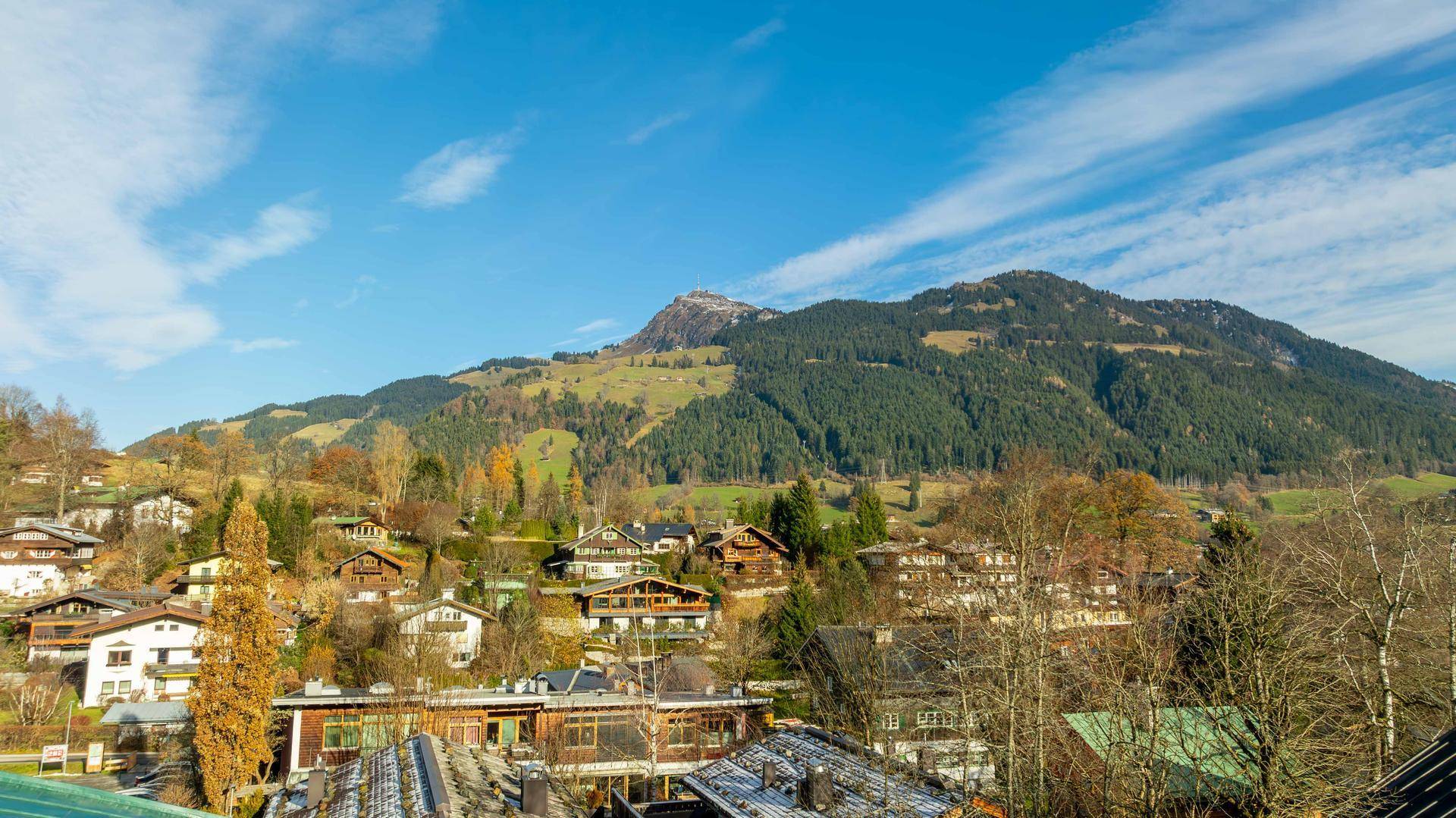 Panoramablick auf ein malerisches Dorf in einer bergigen Landschaft unter blauem Himmel.