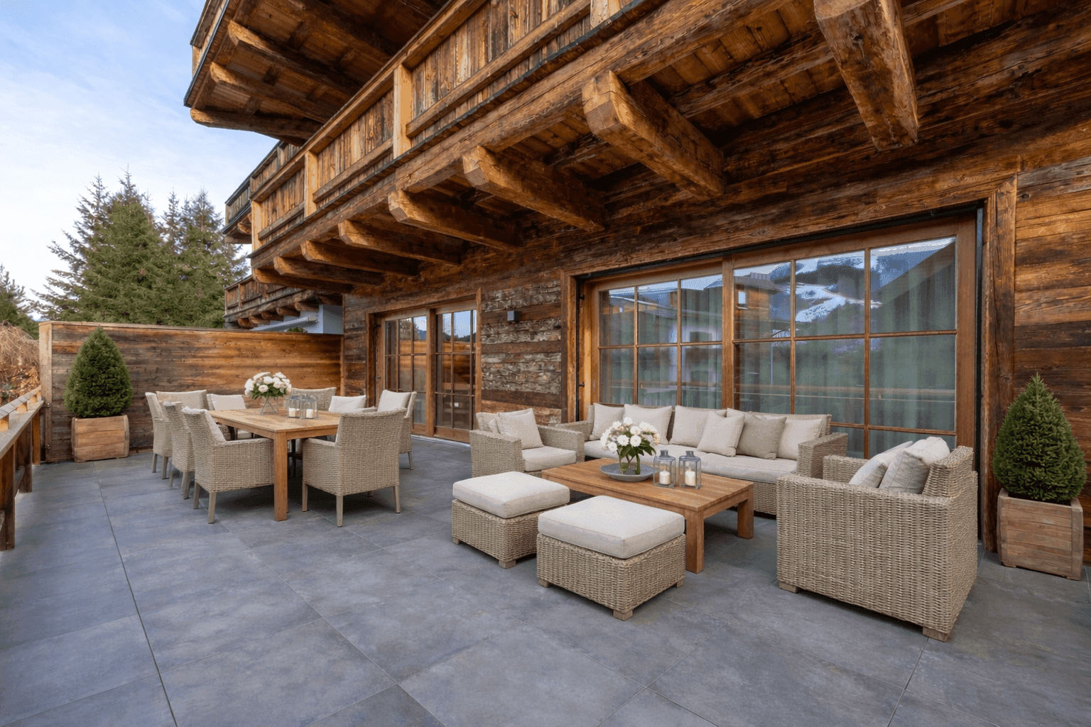 Geräumige Terrasse mit Ess- und Loungebereich, umgeben von einer Holzfassade und Bergblick.